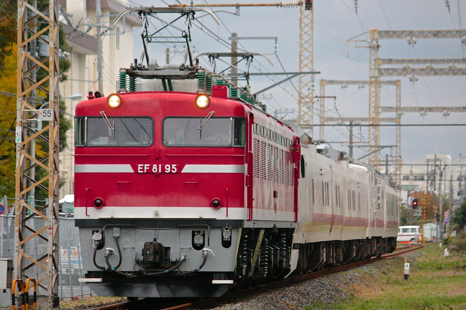 Tren eléctrico rojo circulando por las vías Número de tren EF81 95