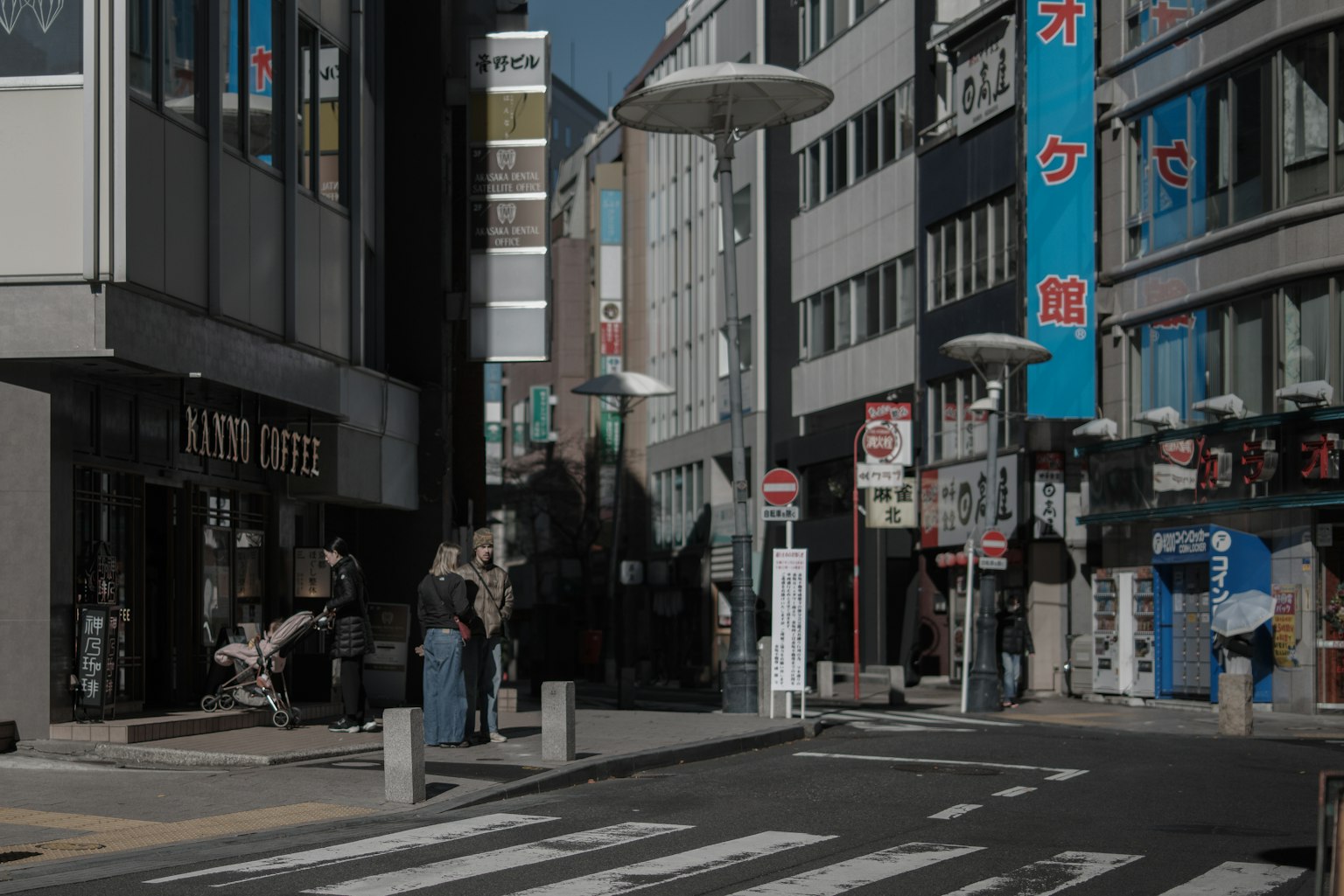 Escena de esquina de calle con personas reunidas y señalización prominente