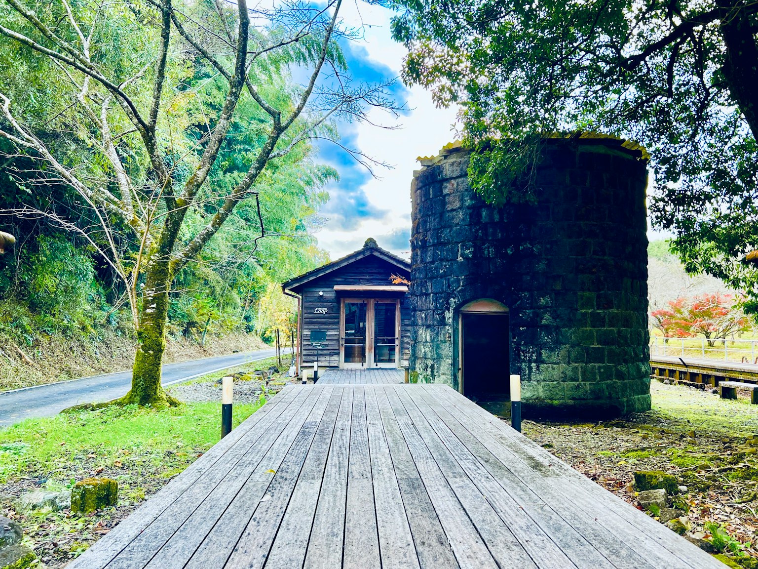 风景包含一个小石头建筑和一个圆柱形结构，周围有木质甲板