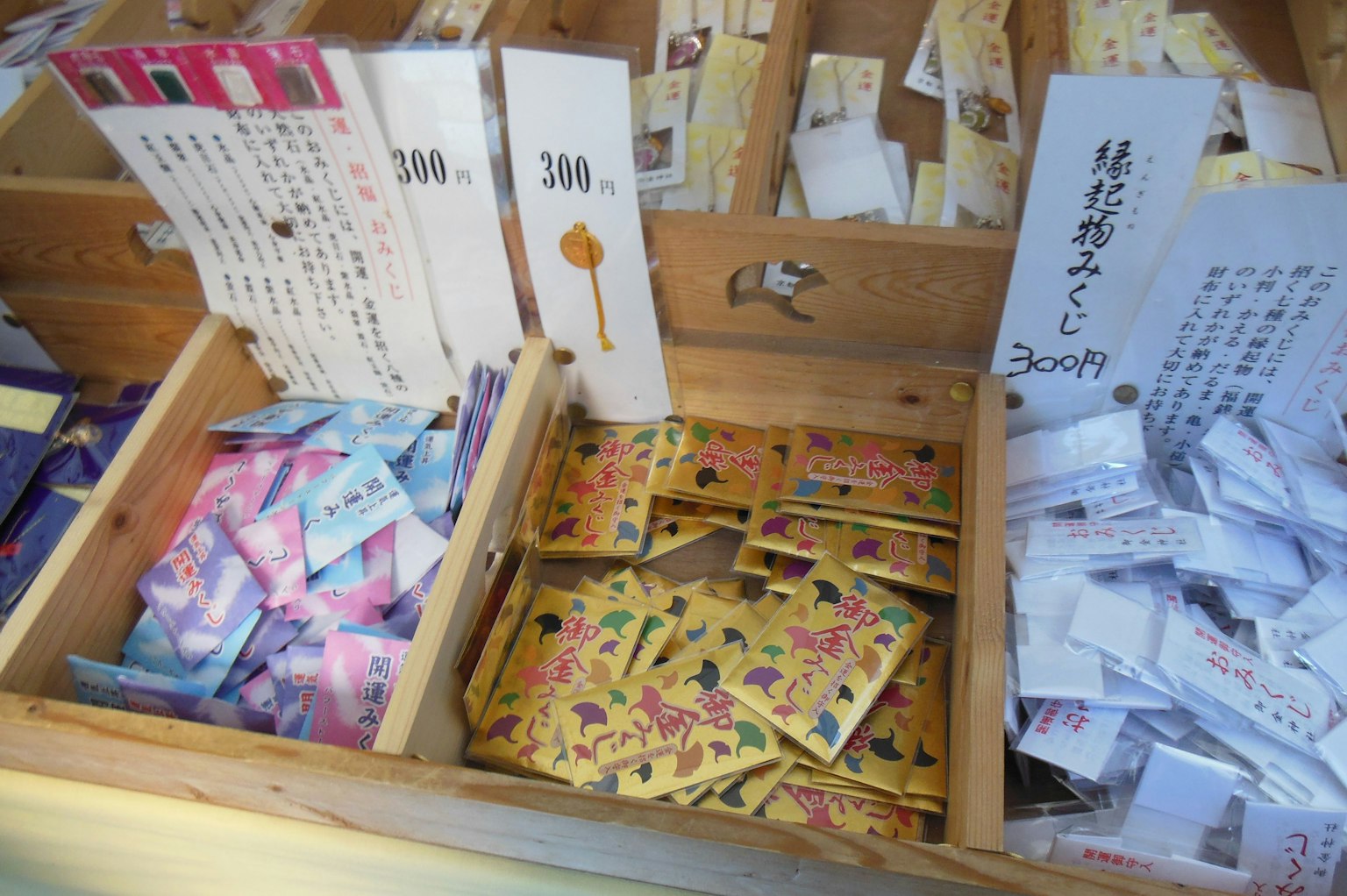 Bùa omamori đầy màu sắc được trưng bày trong hộp gỗ với nhãn giá