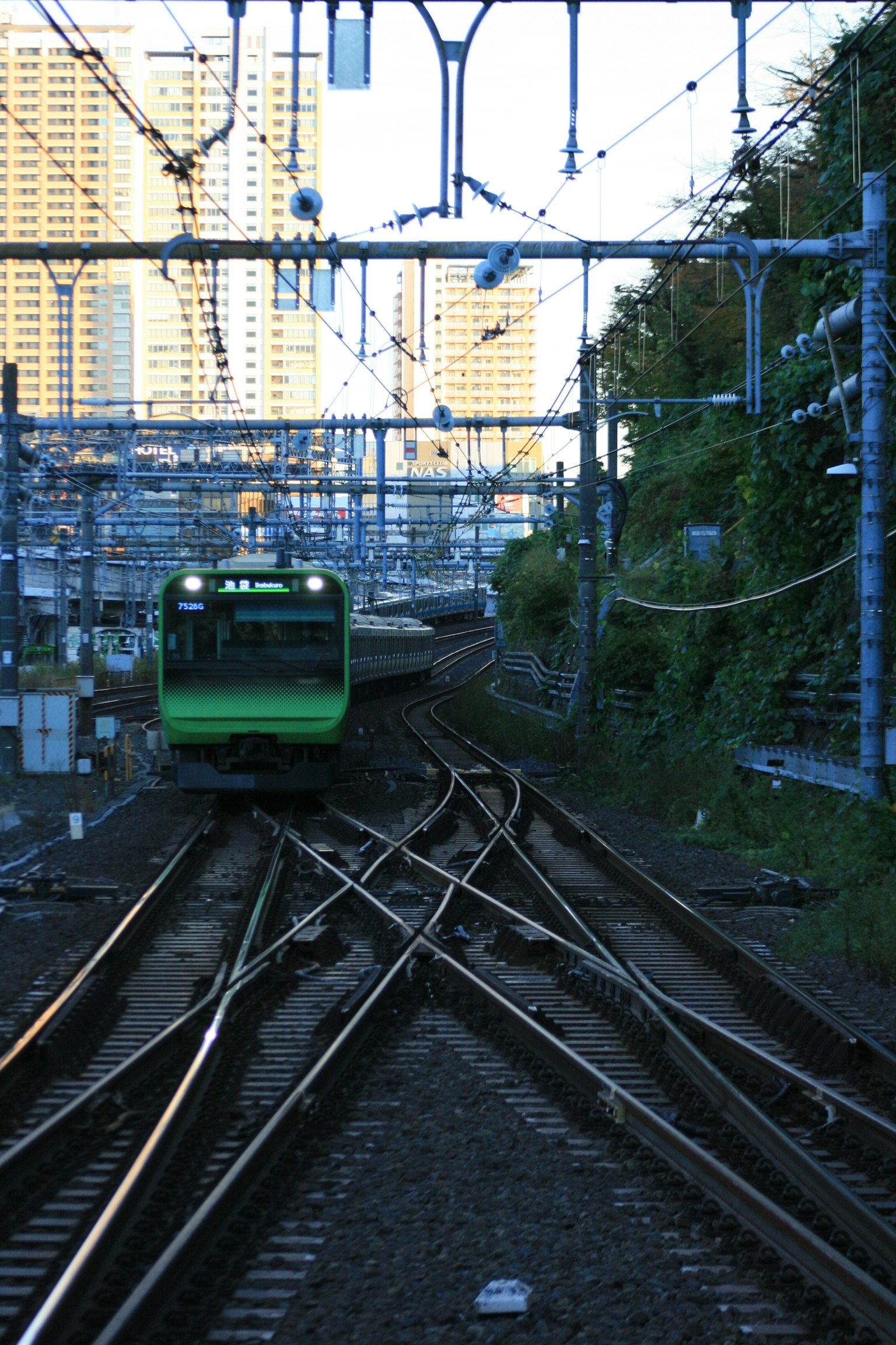 Treno verde che attraversa un complesso di binari in un paesaggio urbano