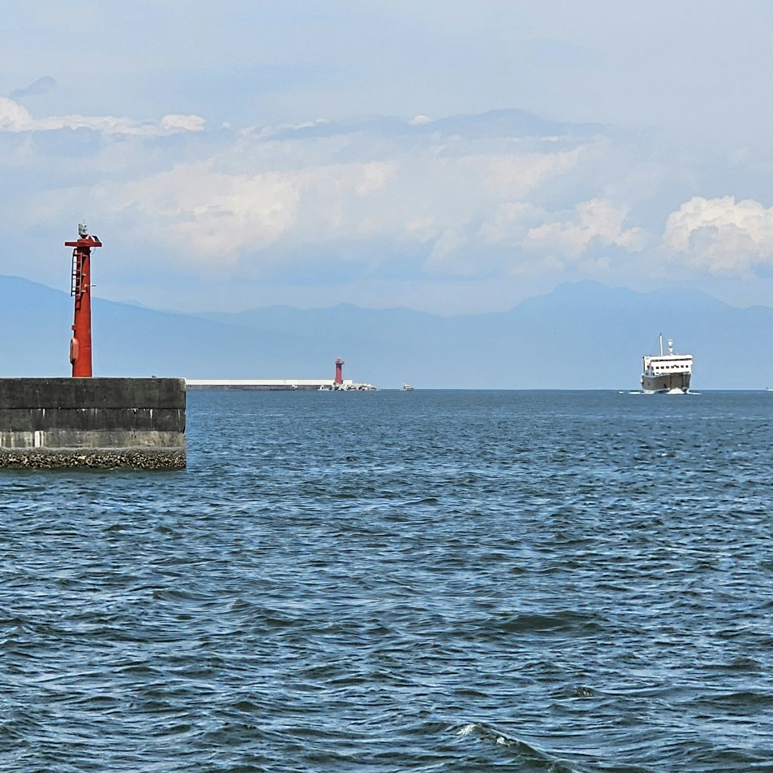 Vista marina con un faro rojo y un barco