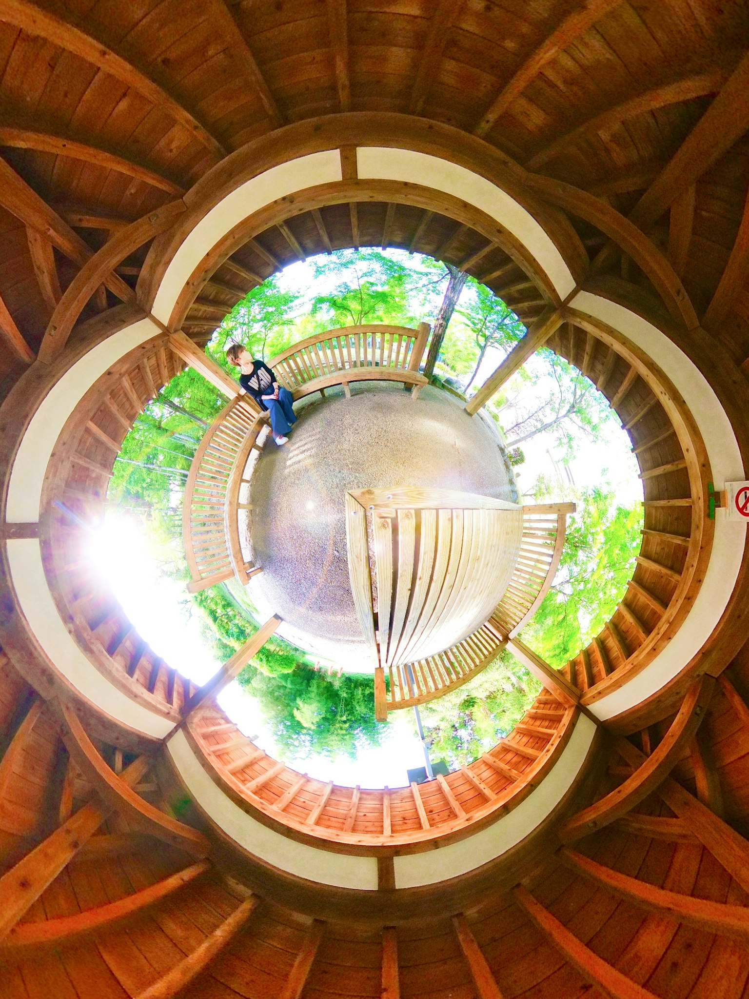 Vista interna di un gazebo in legno con alberi verdi e luce che filtra