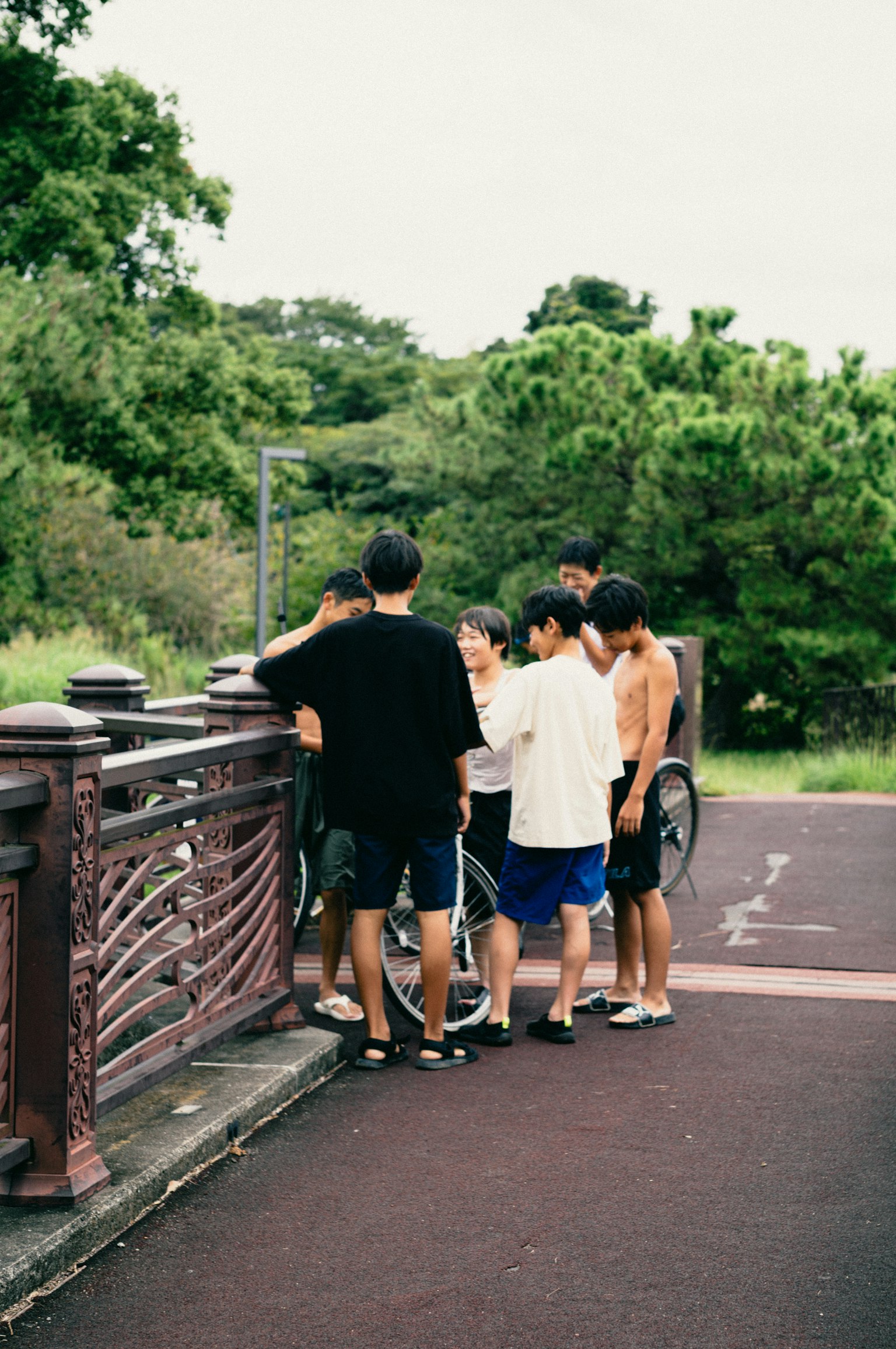 Group of young people gathered around a bridge railing
