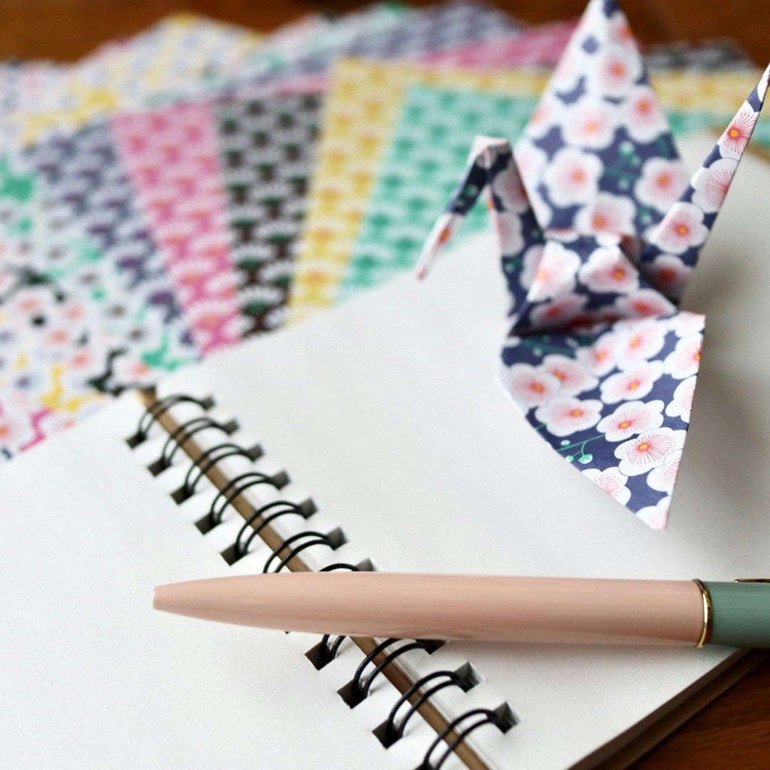 Eine Schreibtischszene mit einem Notizbuch und einem Origami-Kranich