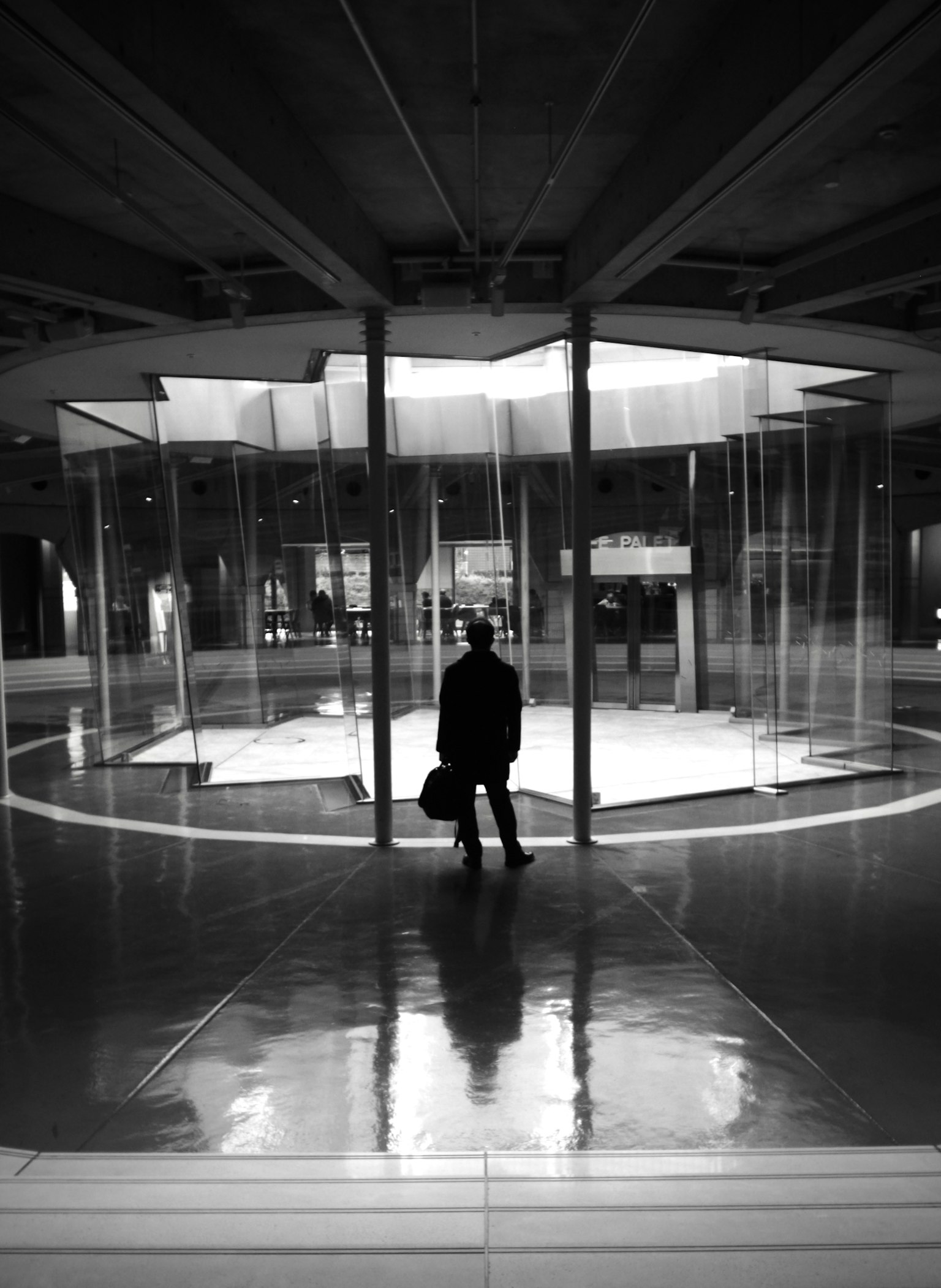 Silhouette di una persona che sta in uno spazio moderno con pareti di vetro