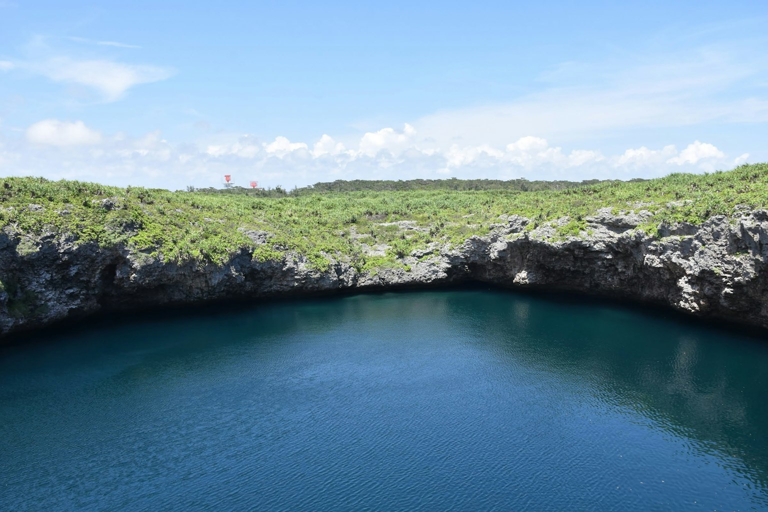 Kratersee mit blauem Wasser umgeben von grünen Hügeln