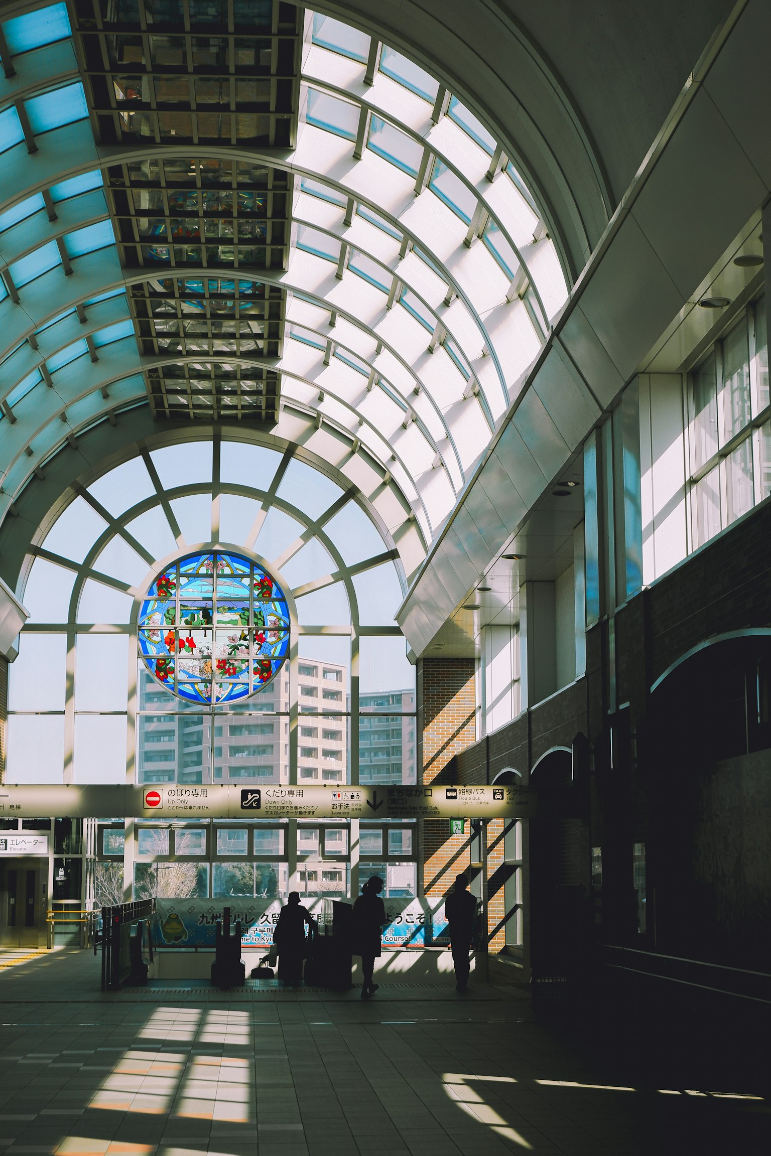 Interior of a train station with a bright glass ceiling and people walking