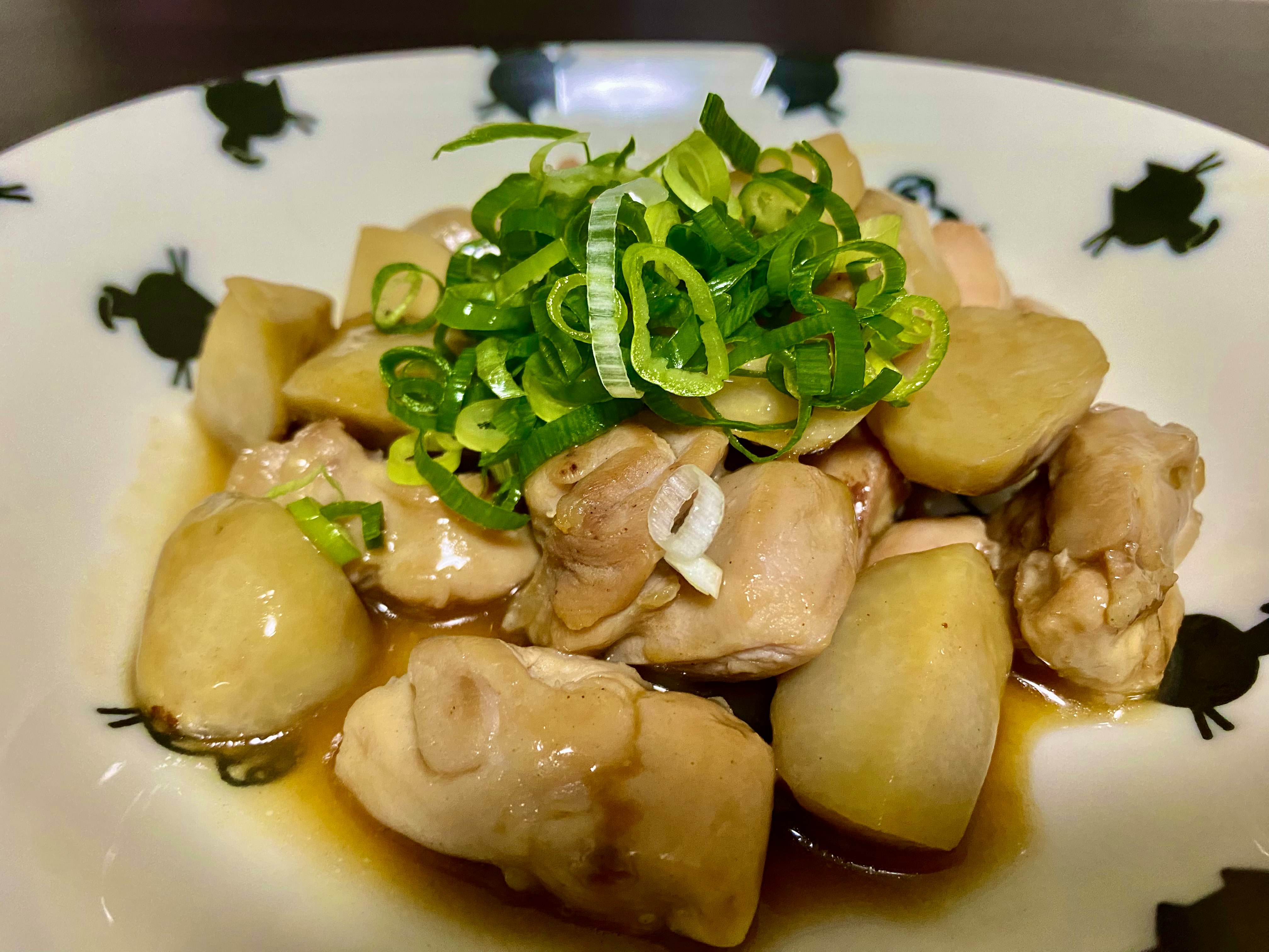 白盤上的燉雞與馬鈴薯，點綴蔥花