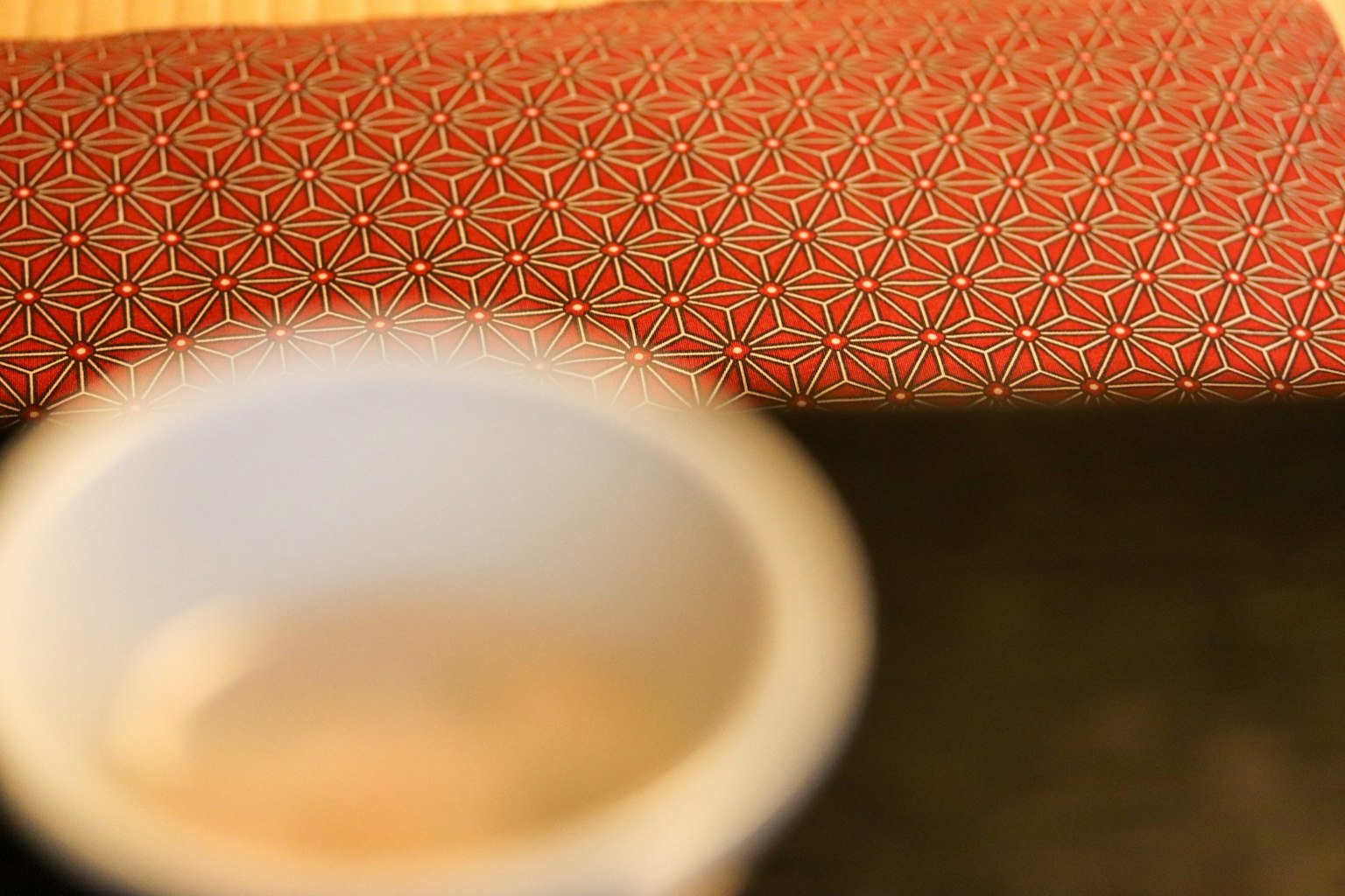 Mangkuk teh putih di atas kain bermotif geometris merah