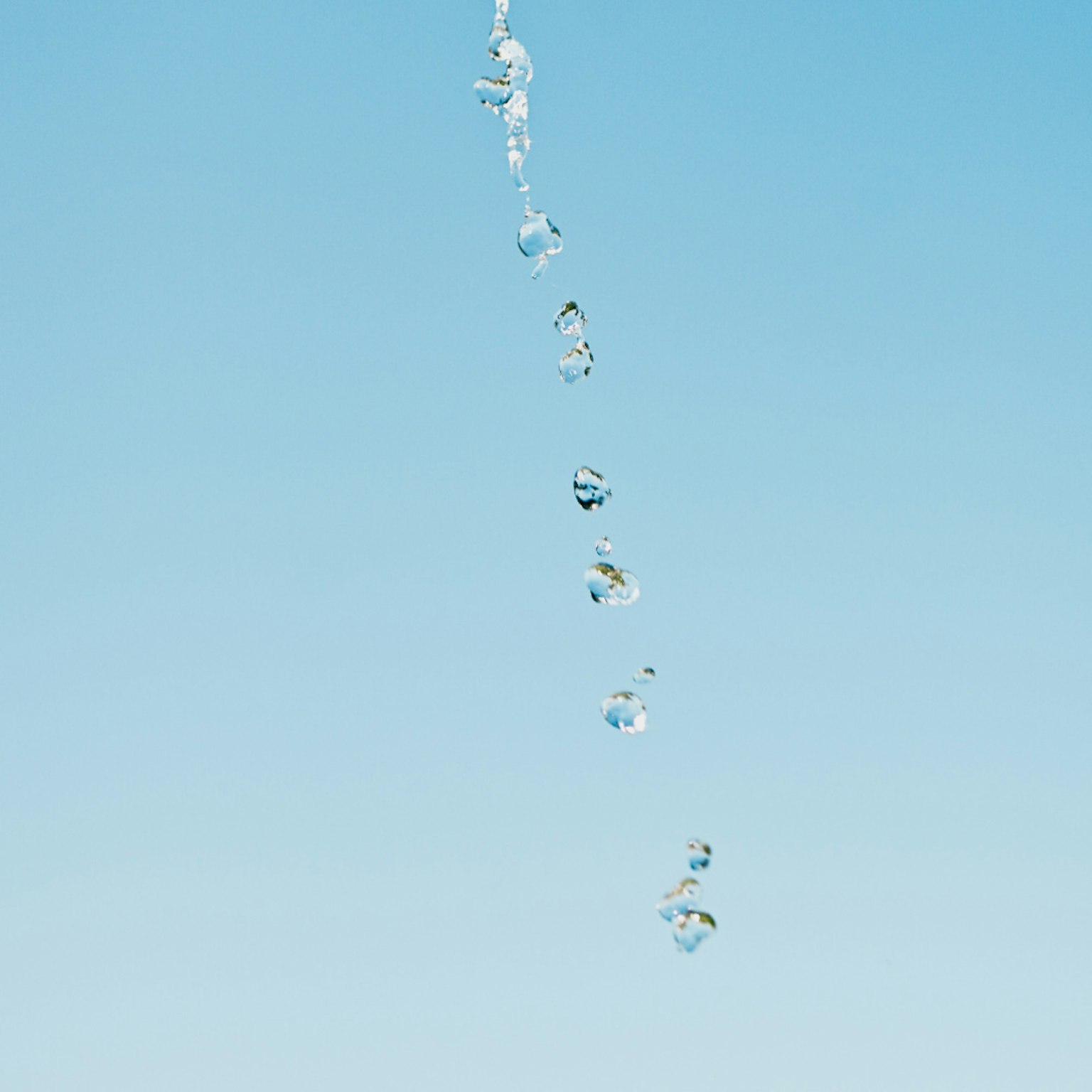 Water droplets falling against a clear blue sky