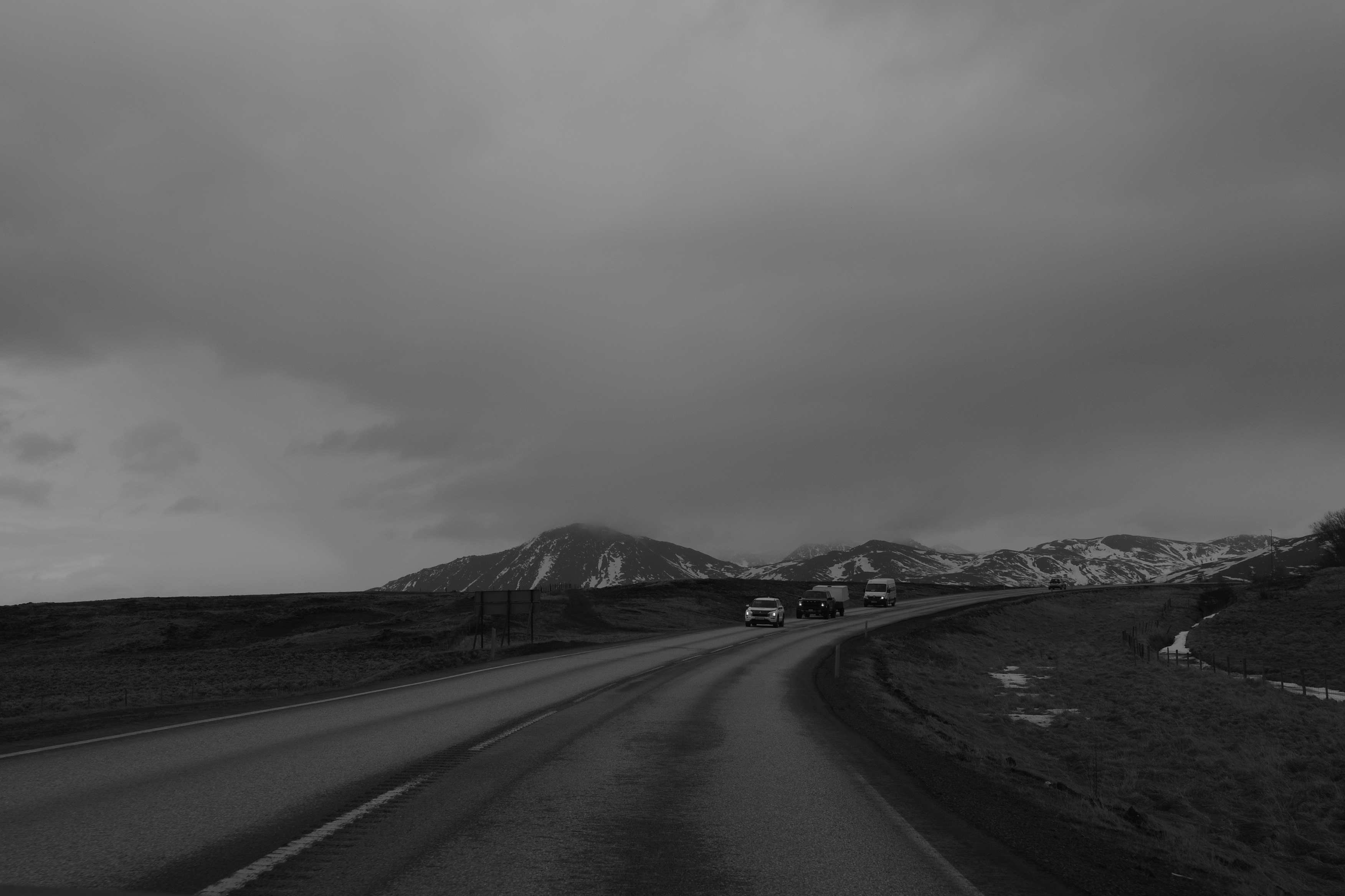 嵐の前の曇天の山道を走る車のある風景