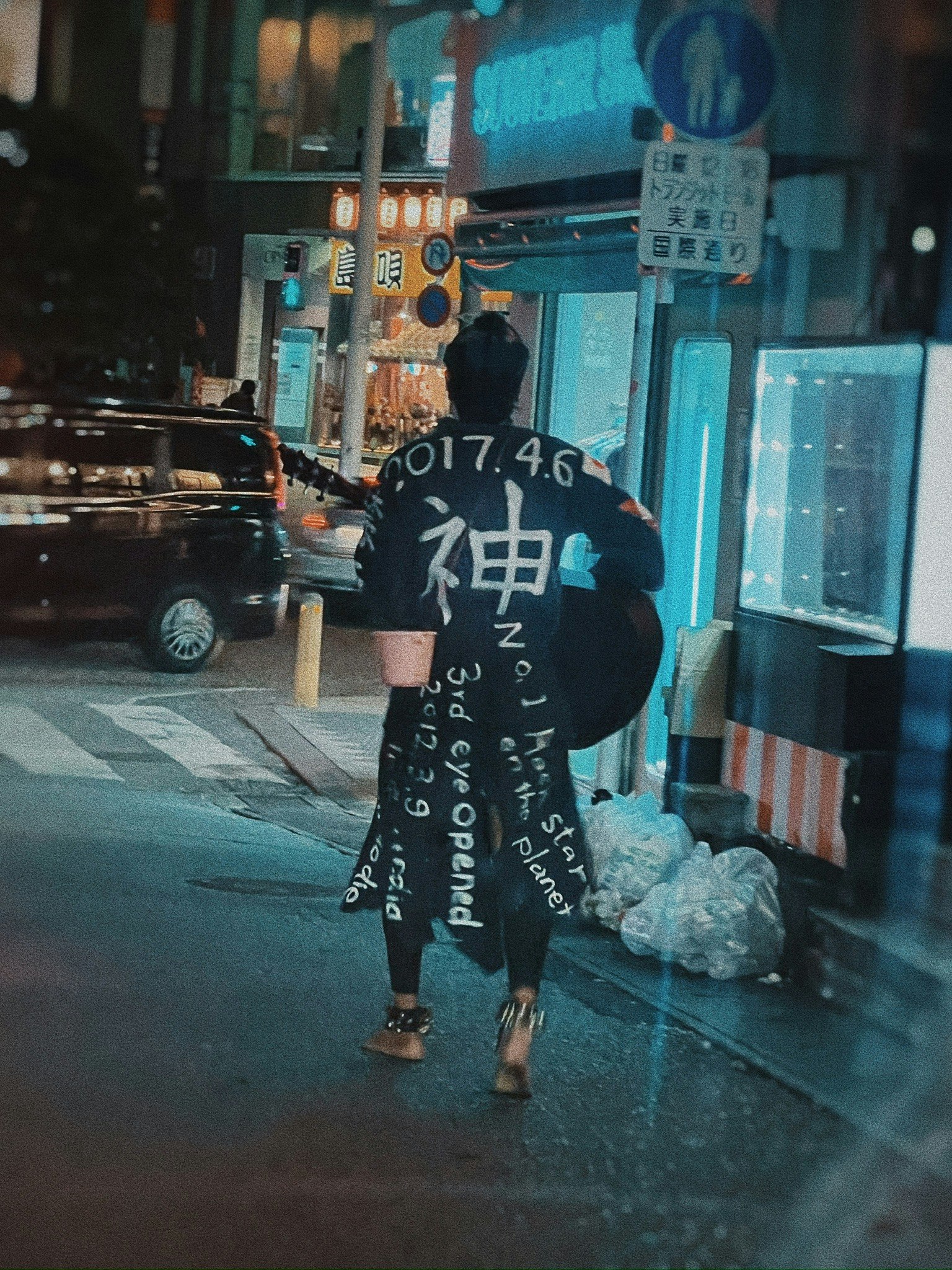 Person wearing a costume with kanji characters walking in a night street
