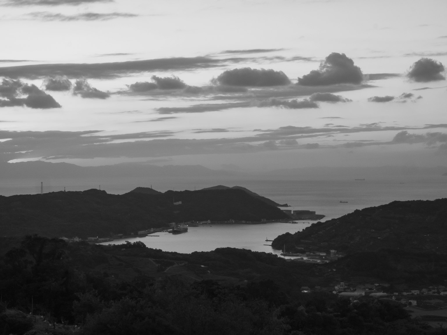 Schwarz-weiß Küstenlandschaft mit Bergen und Wolken in der Dämmerung