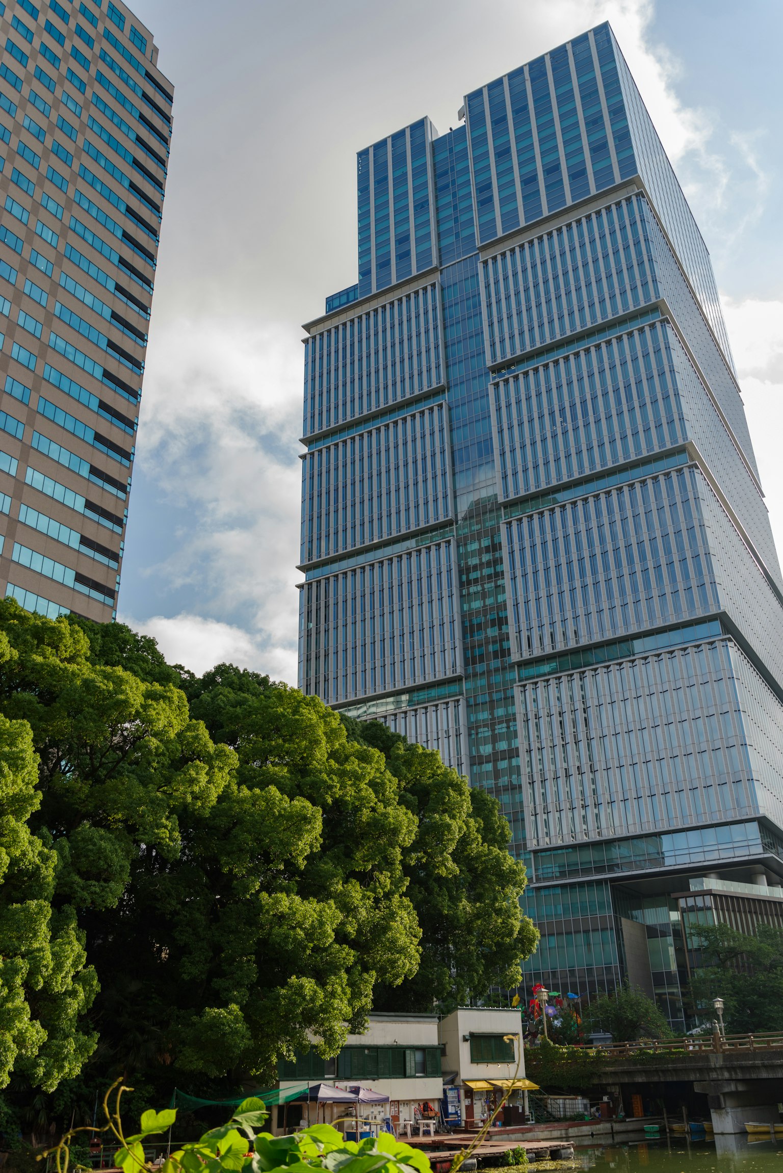 Tall skyscraper with reflective glass and lush green trees