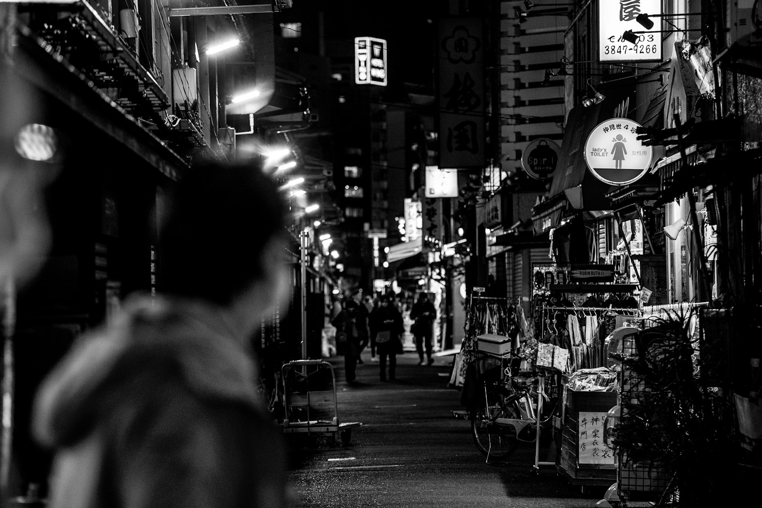 Cảnh đường phố đen trắng với người đi bộ và biển hiệu đèn neon sáng vào ban đêm