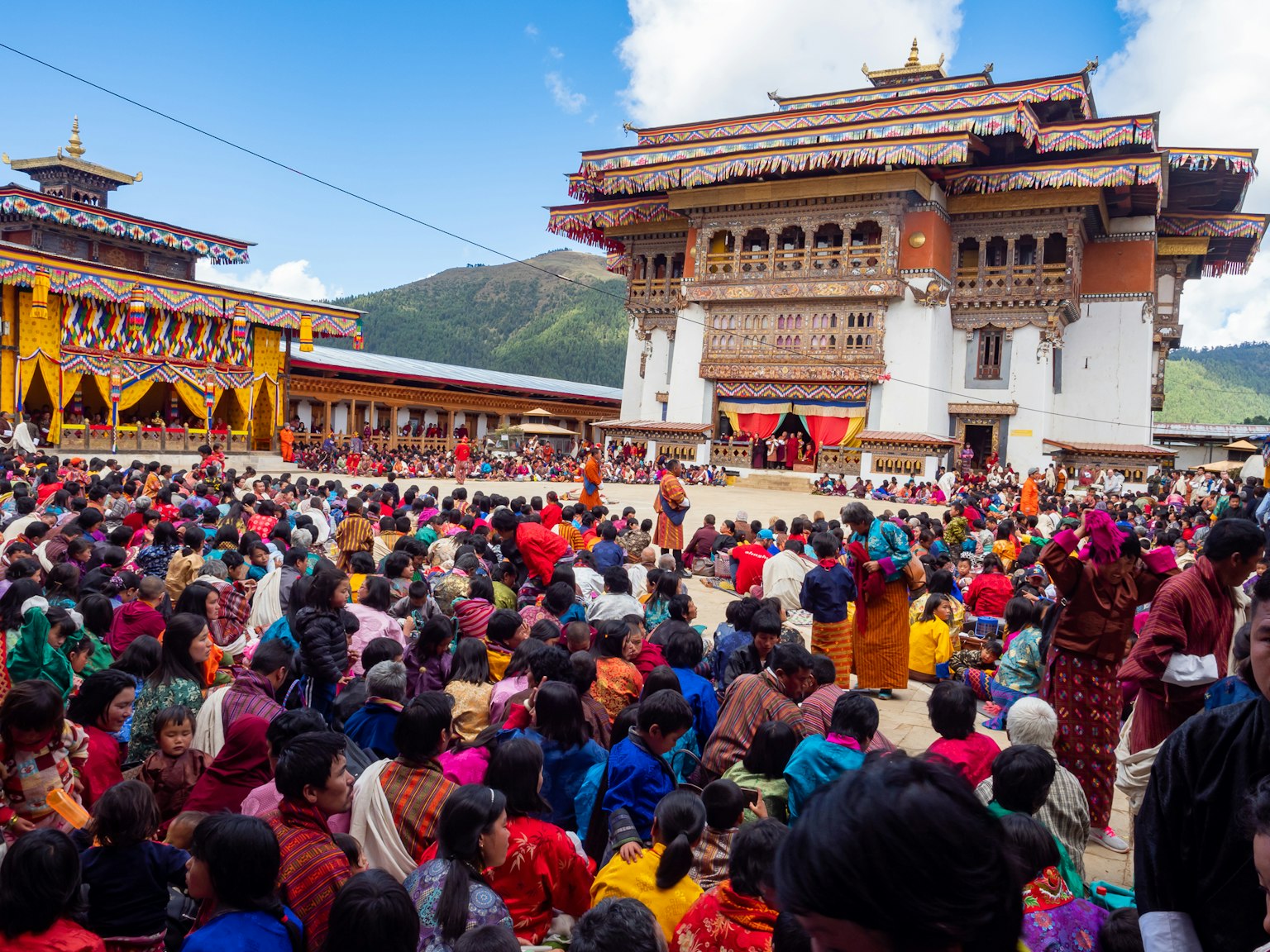 Folla riunita a un festival tradizionale in Bhutan con abbigliamento colorato e architettura
