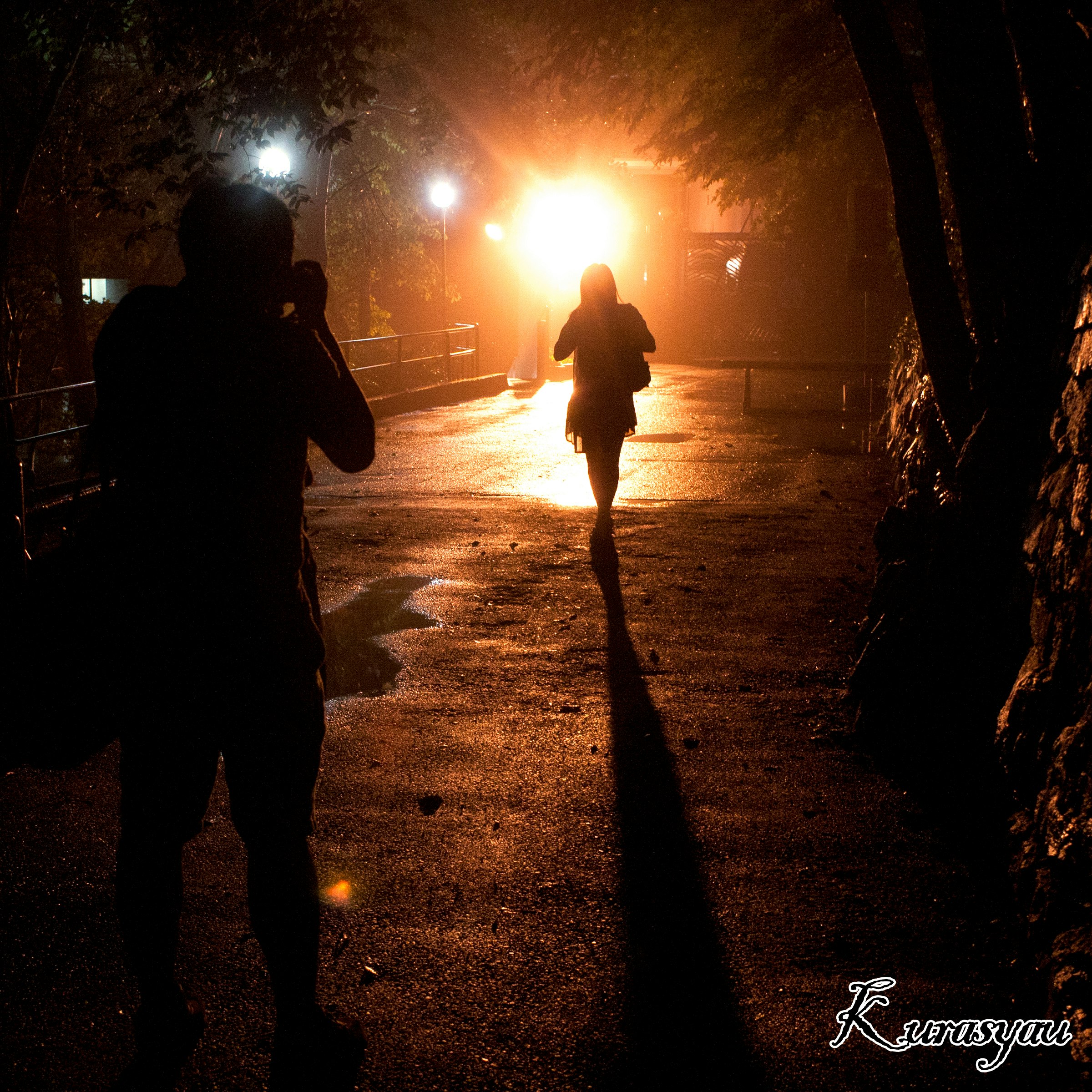 夜の路地を歩くシルエットの人々