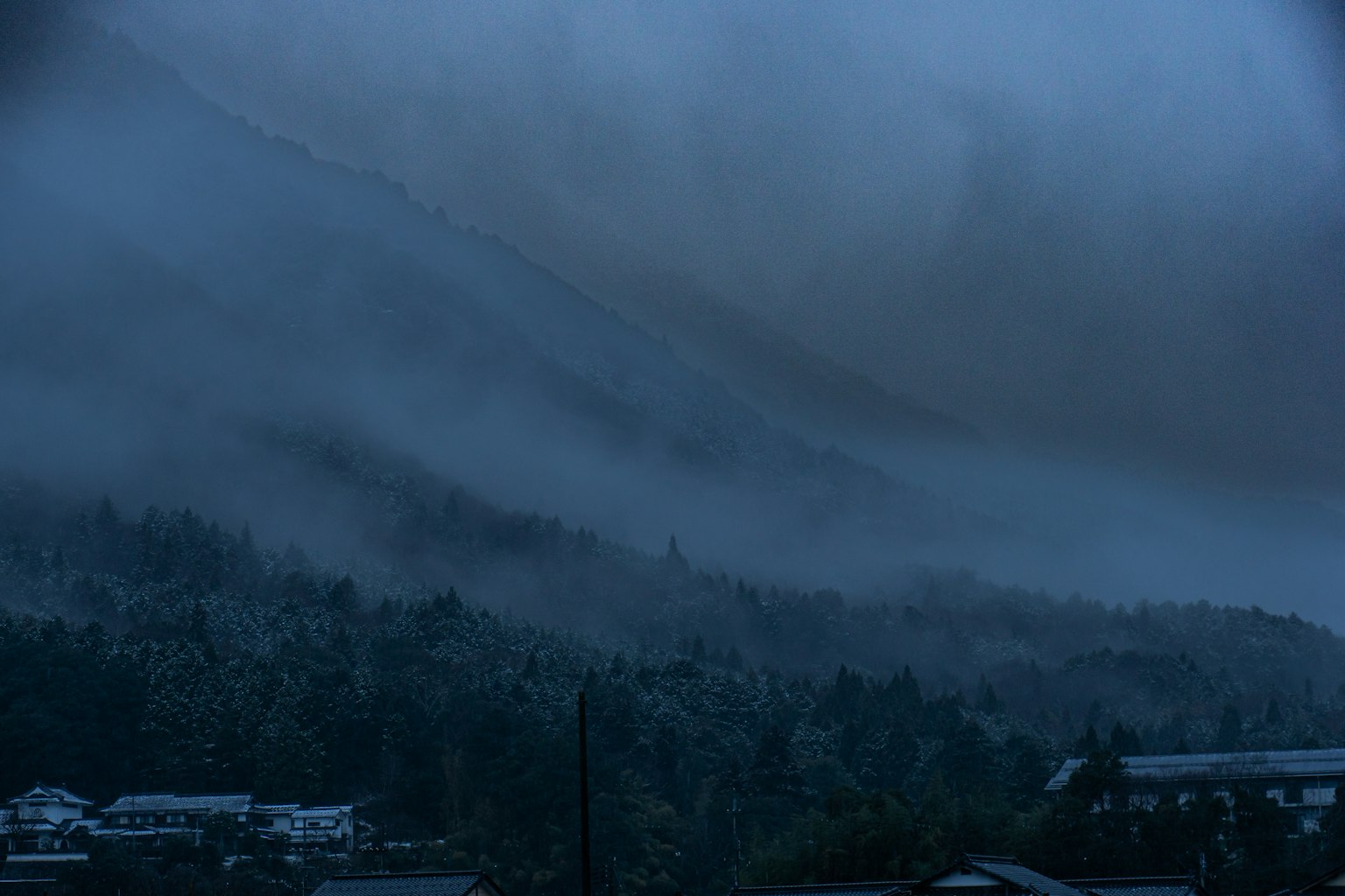 Paysage de montagne brumeux et bleu avec des maisons