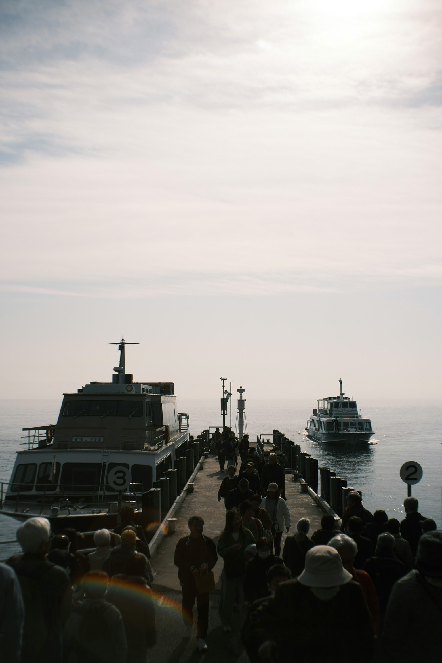 Kerumunan orang di dermaga dengan kapal di dekatnya