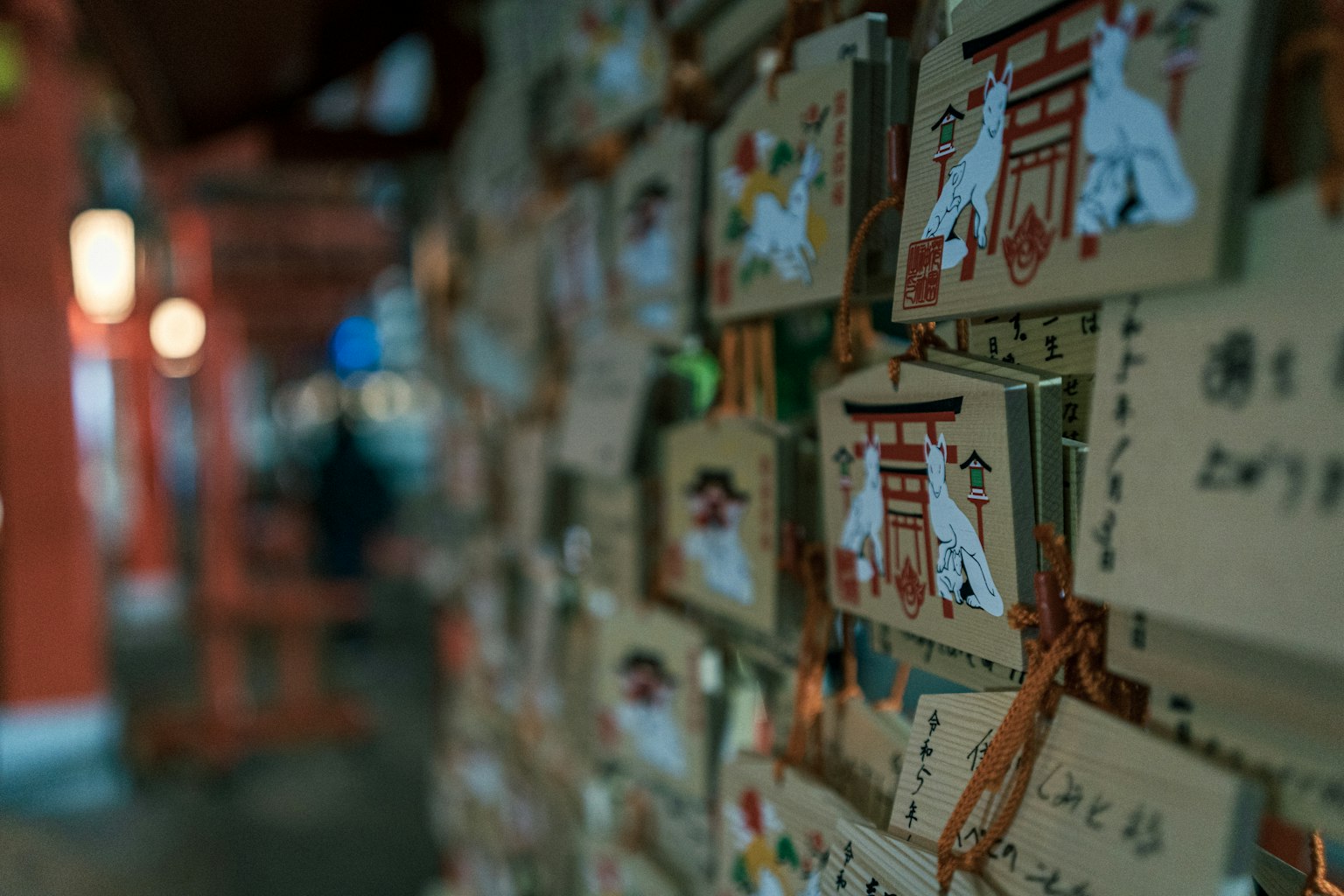 Una pared de placas ema en un santuario con diseños coloridos y texto en japonés