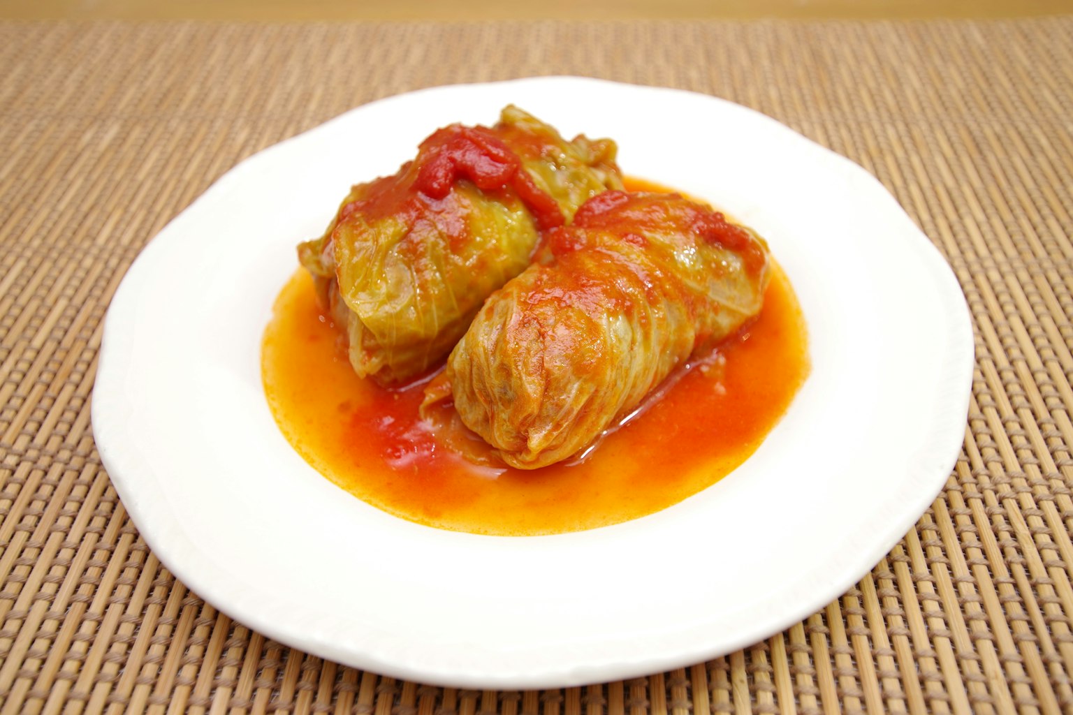 Rollos de repollo cubiertos con salsa de tomate en un plato blanco