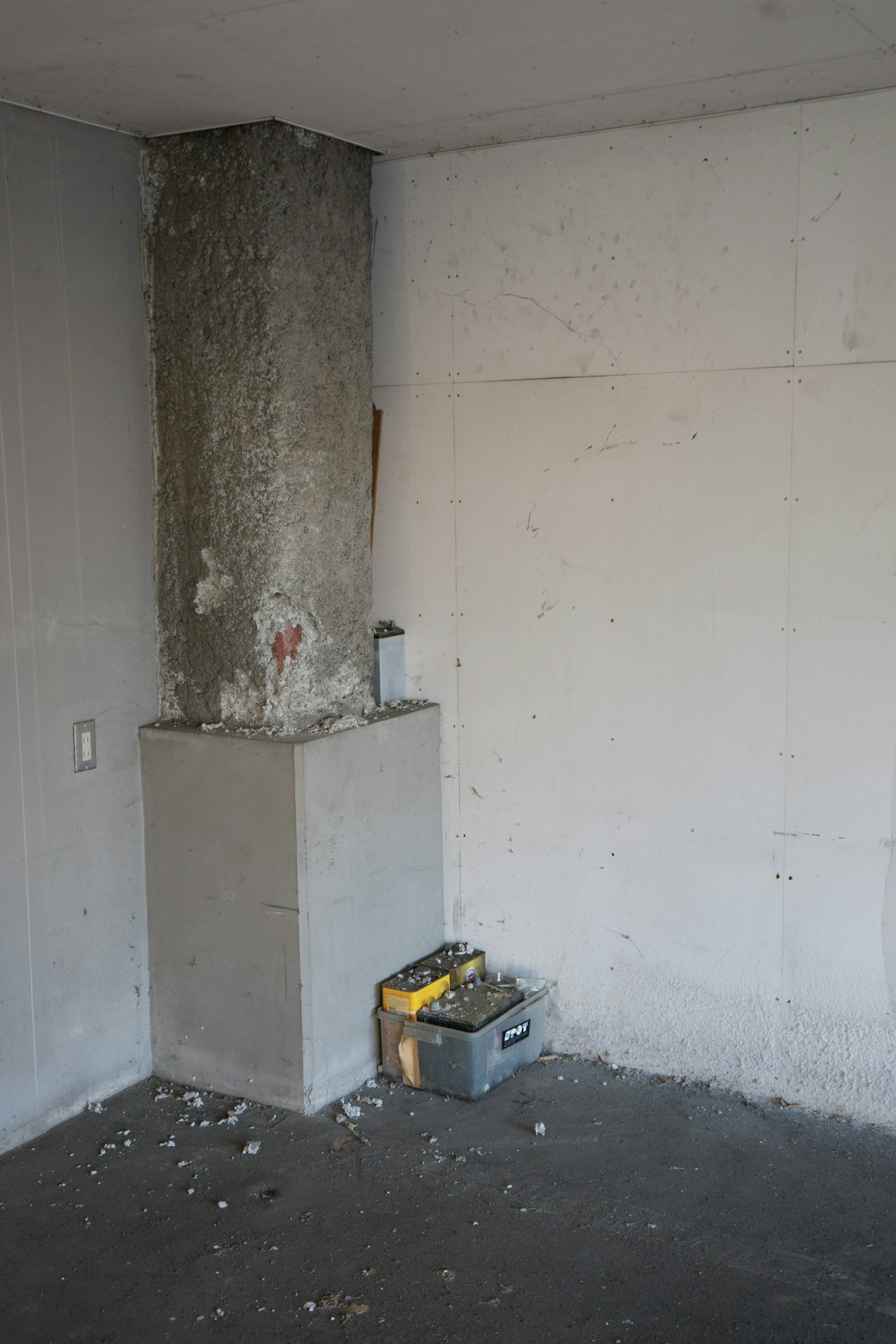 Pilar de concreto en una esquina de una habitación con una caja de herramientas en el suelo