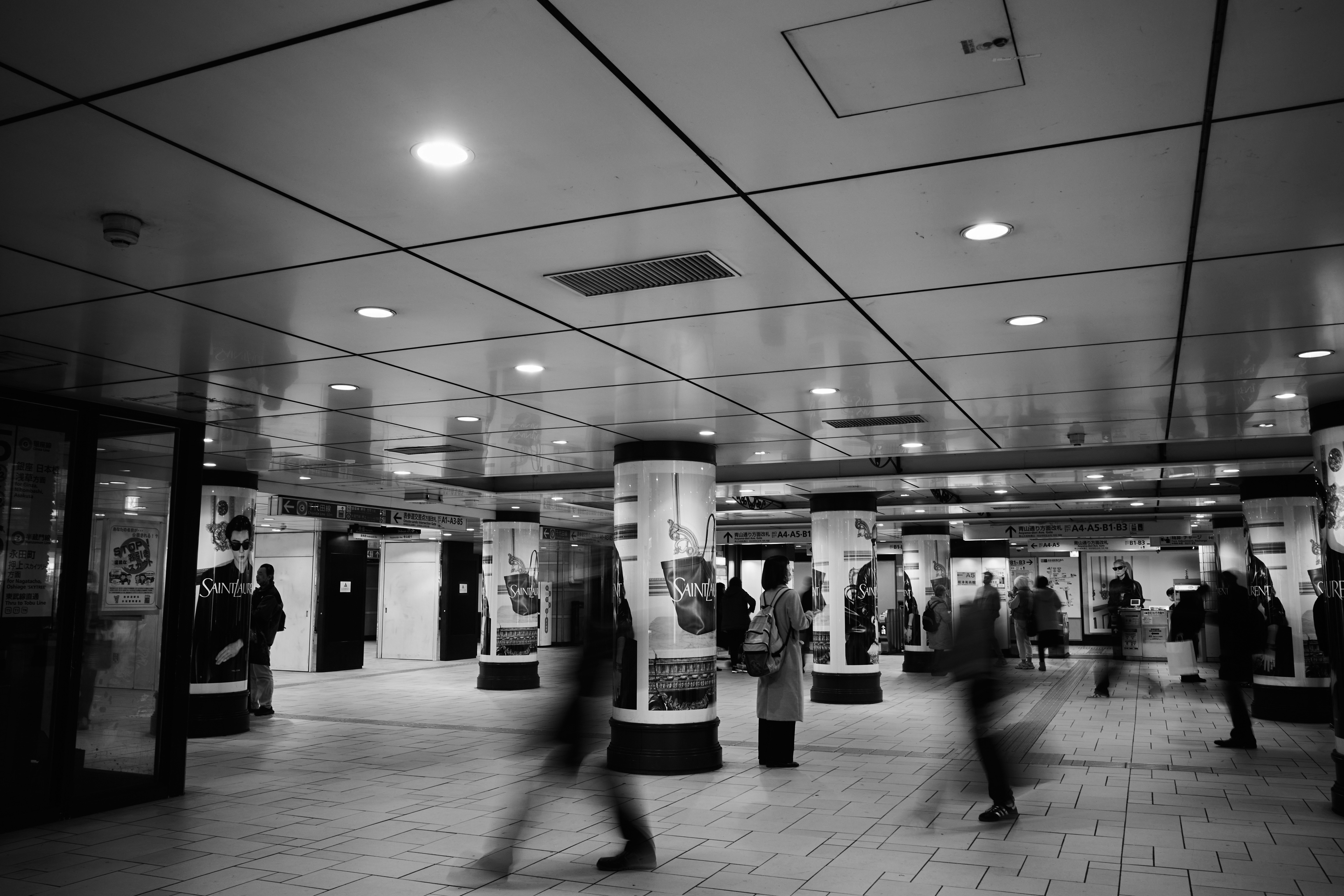Menschen gehen in einer Bahnhofshalle nahe den Drehkreuzen entlang
