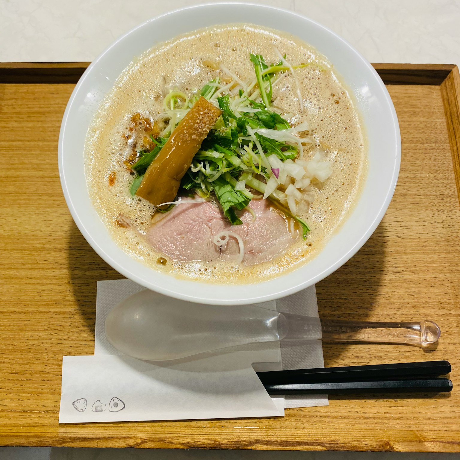 Ramen avec bouillon crémeux garni de porc tranché et d'oignons verts