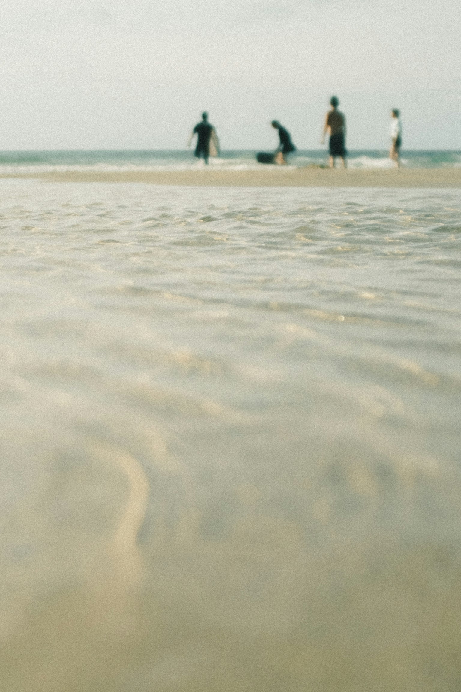 ผู้คนเล่นอยู่ที่ชายหาดกับคลื่นที่นุ่มนวล