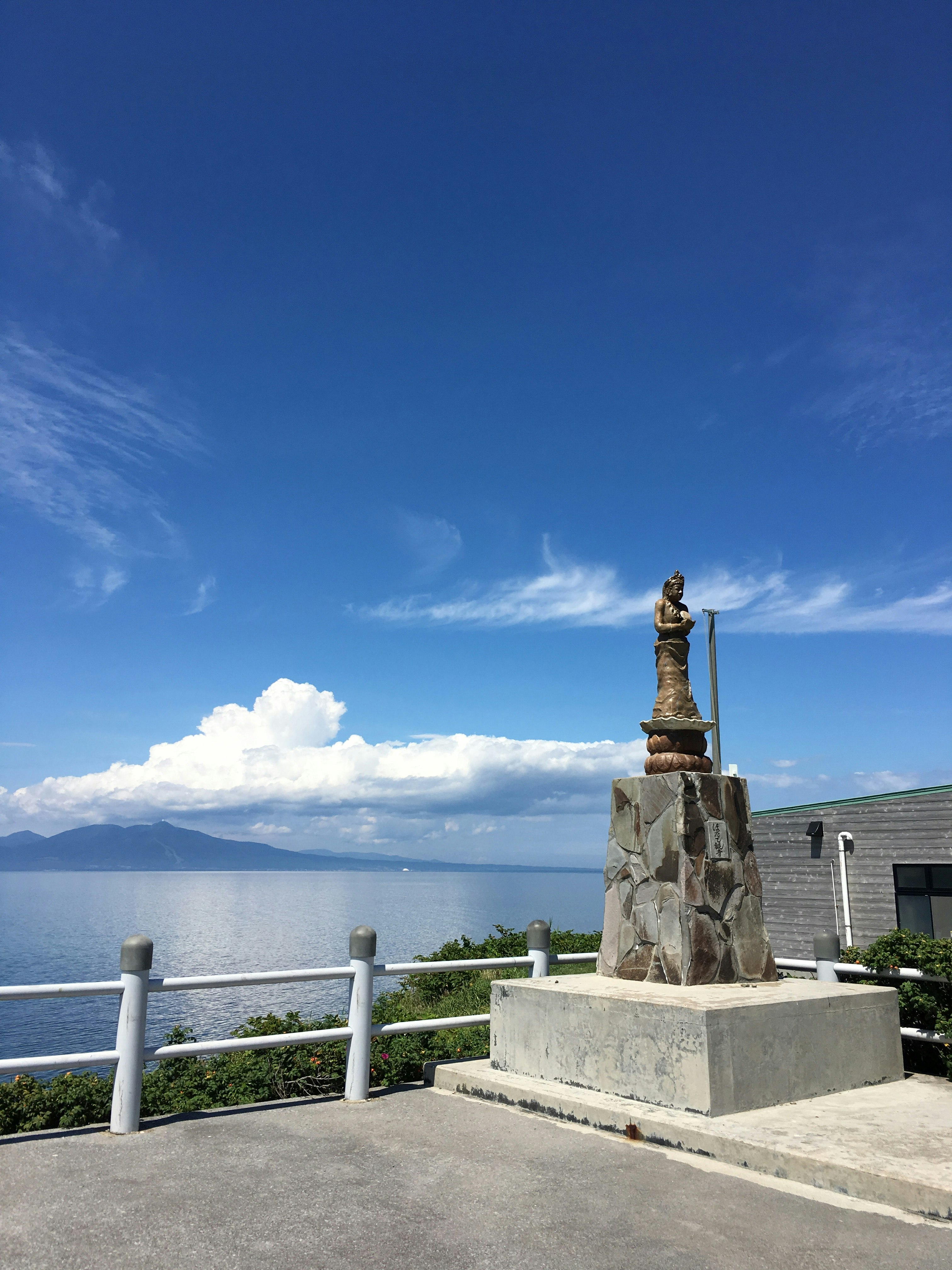 青空の下、海辺の展望台に積まれた石のモニュメント