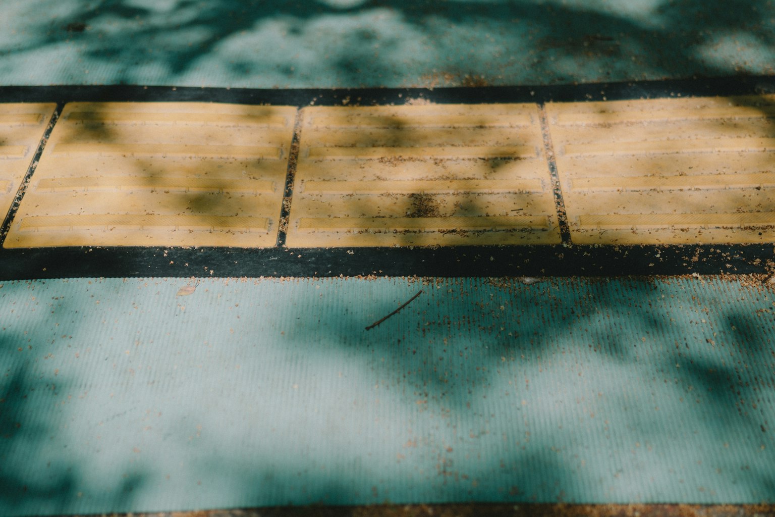 Ein Abschnitt blauer Boden mit gelb-braunen Holzplanken und verstreuten Schatten