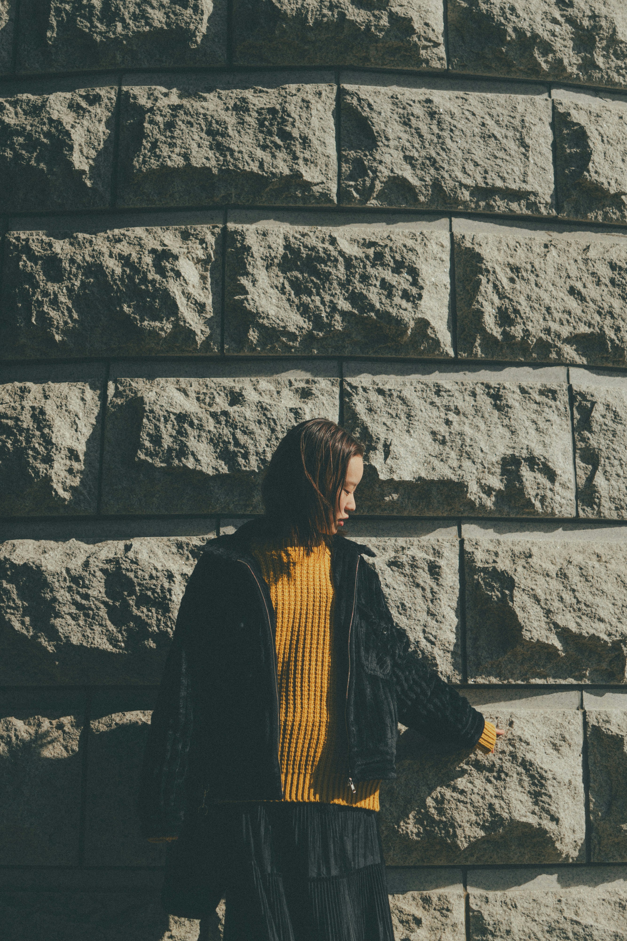 person standing in front of a stone wall