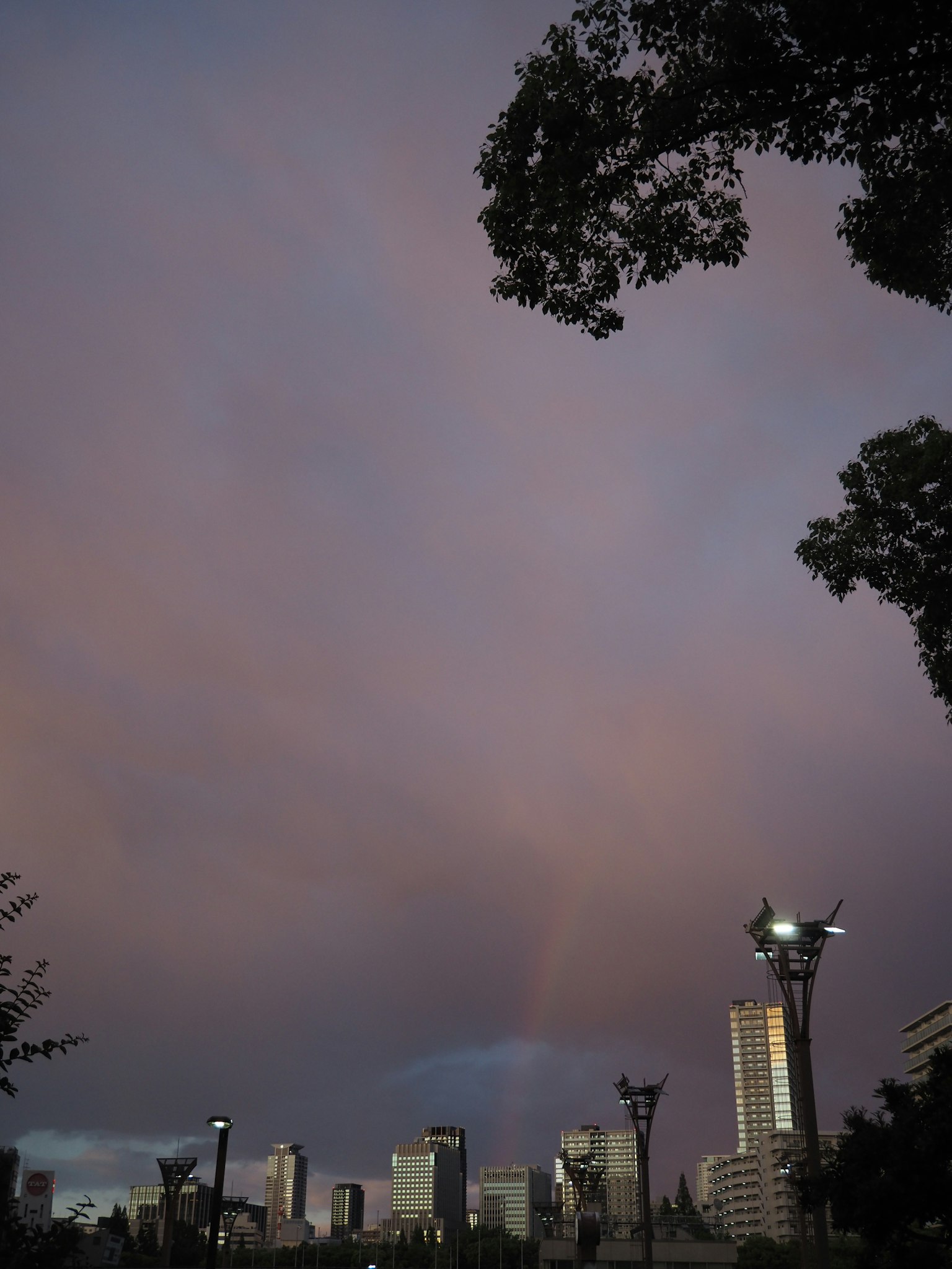 Paysage urbain avec un arc-en-ciel sous un ciel de coucher de soleil