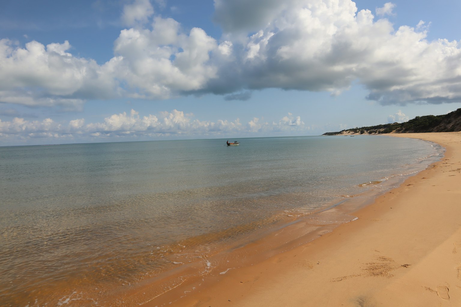 Pantai indah dengan air tenang dan langit berawan