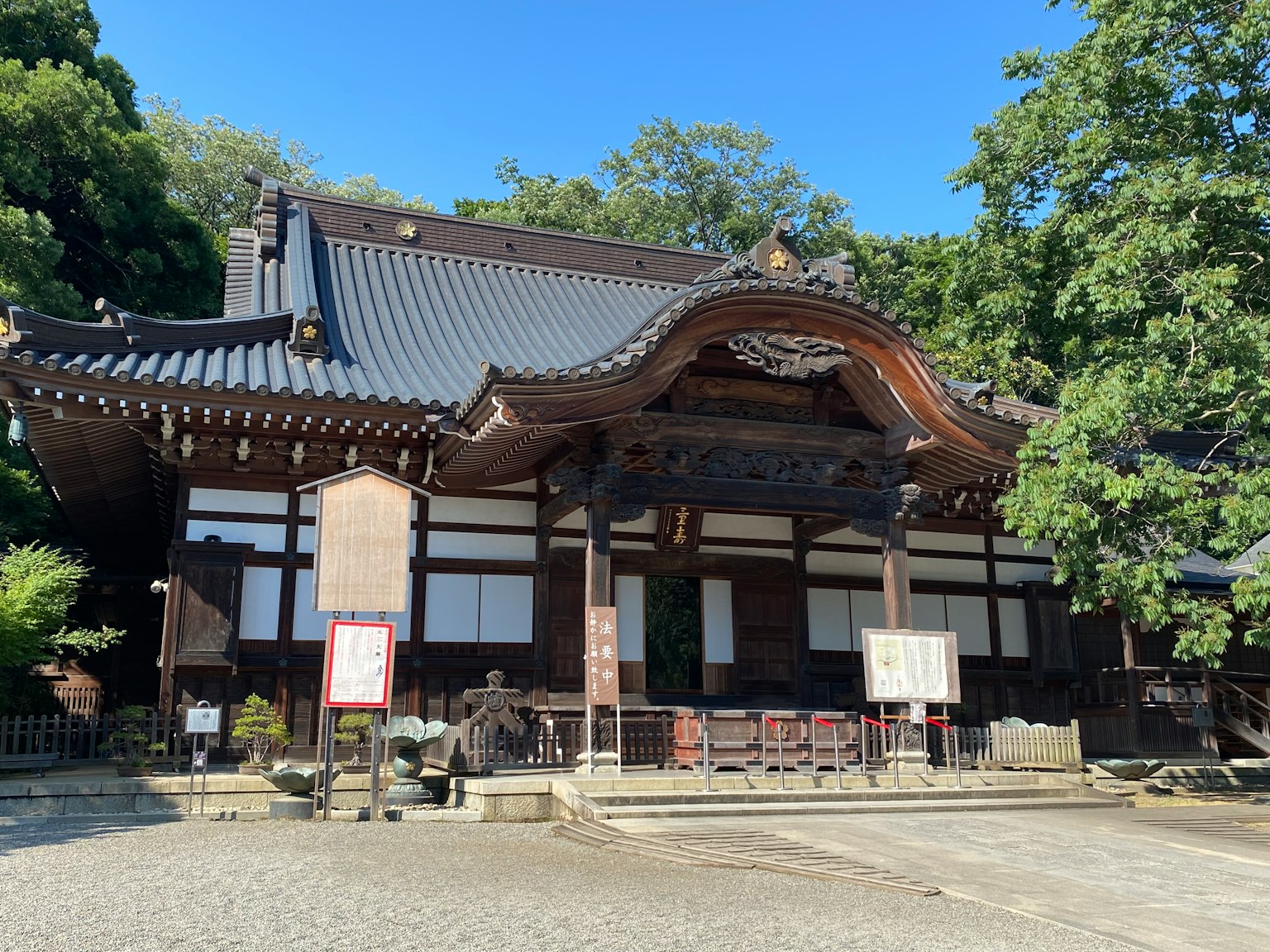 传统日本寺庙外观，被郁郁葱葱的绿树环绕，具有独特的屋顶设计