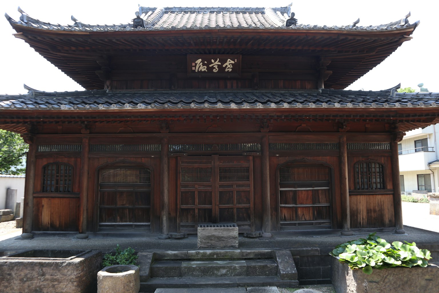Edificio japonés tradicional de madera con techo de tejas y letrero tallado