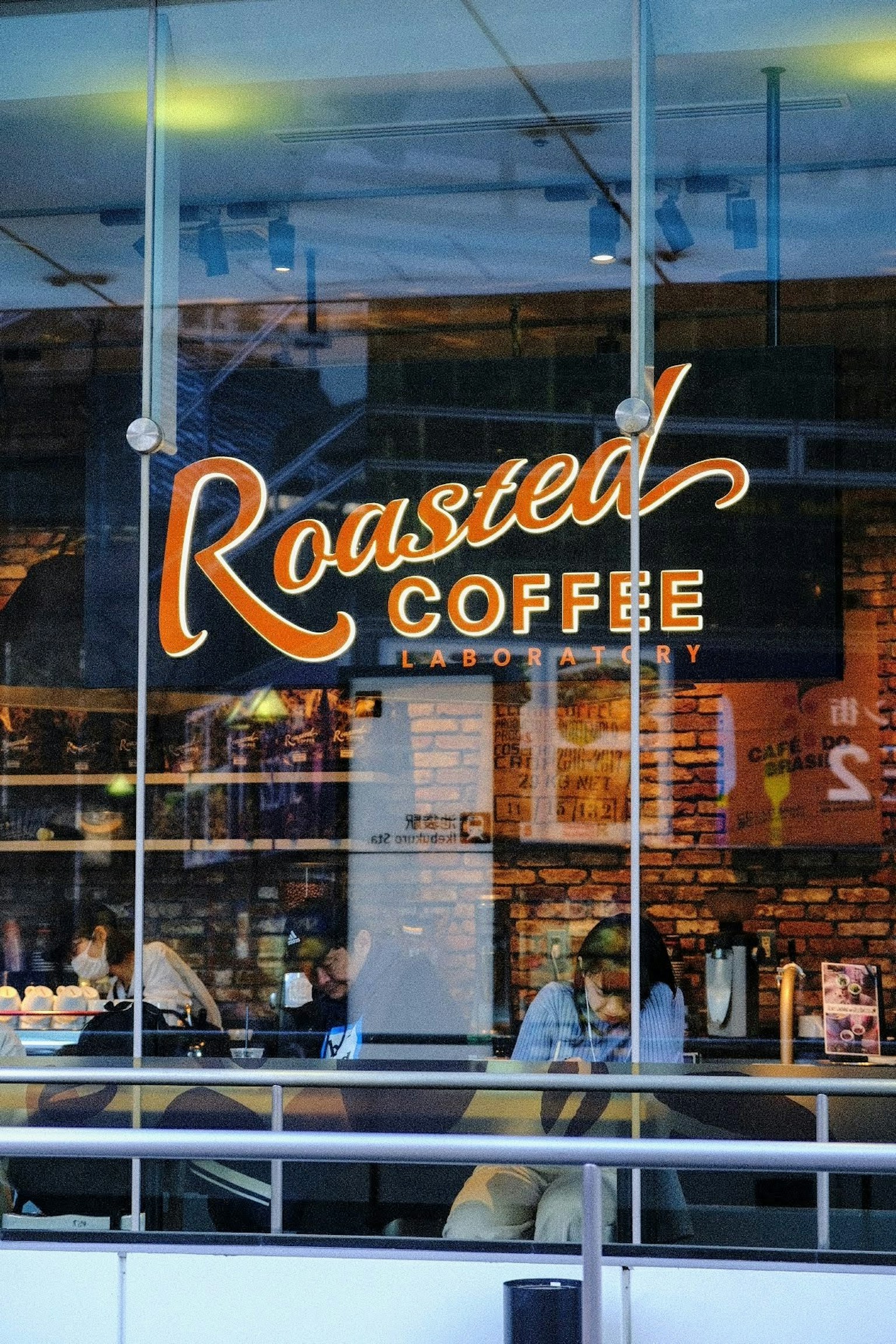 Cảnh cửa sổ quán cà phê có biển hiệu Roasted Coffee