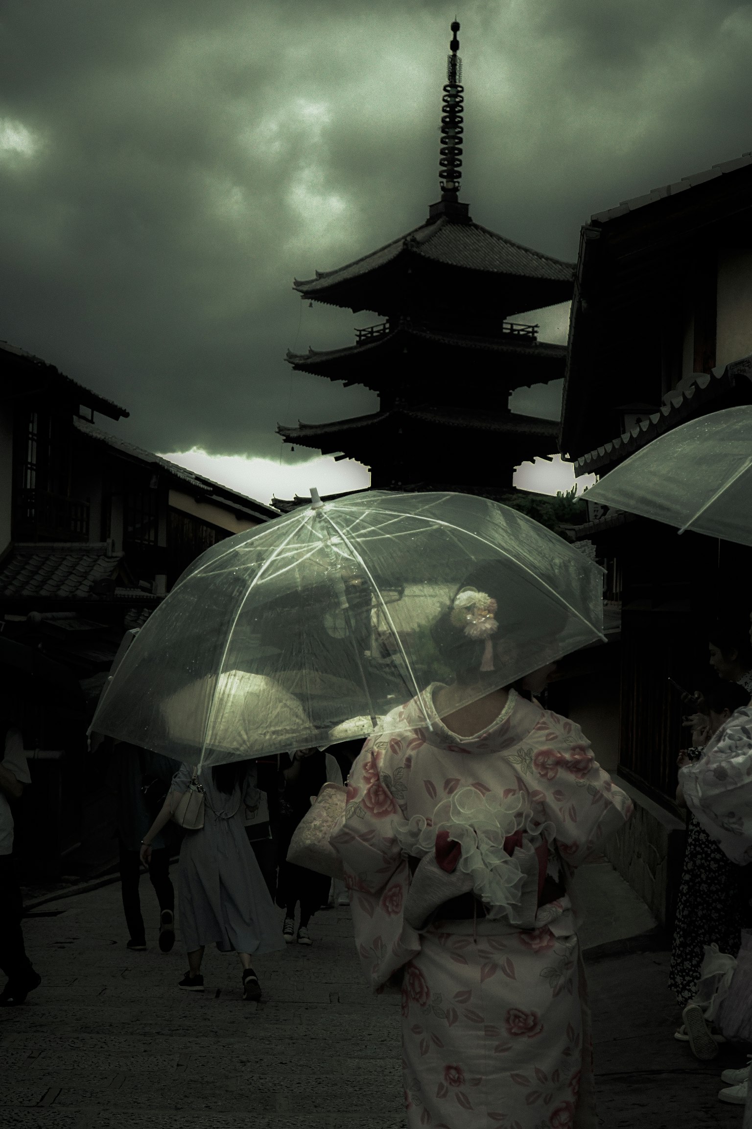 Eine Frau in traditioneller Kleidung, die mit einem Regenschirm unter dunklen Wolken geht