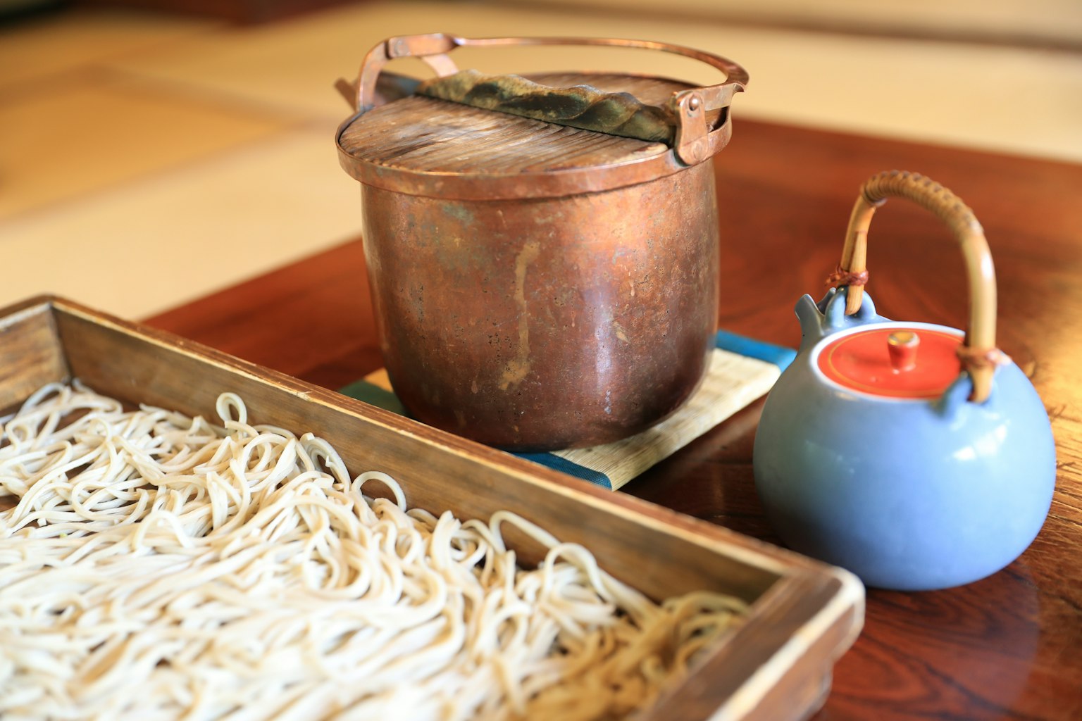 鍋裡的麵條和木托盤上的麵條以及藍色茶壺