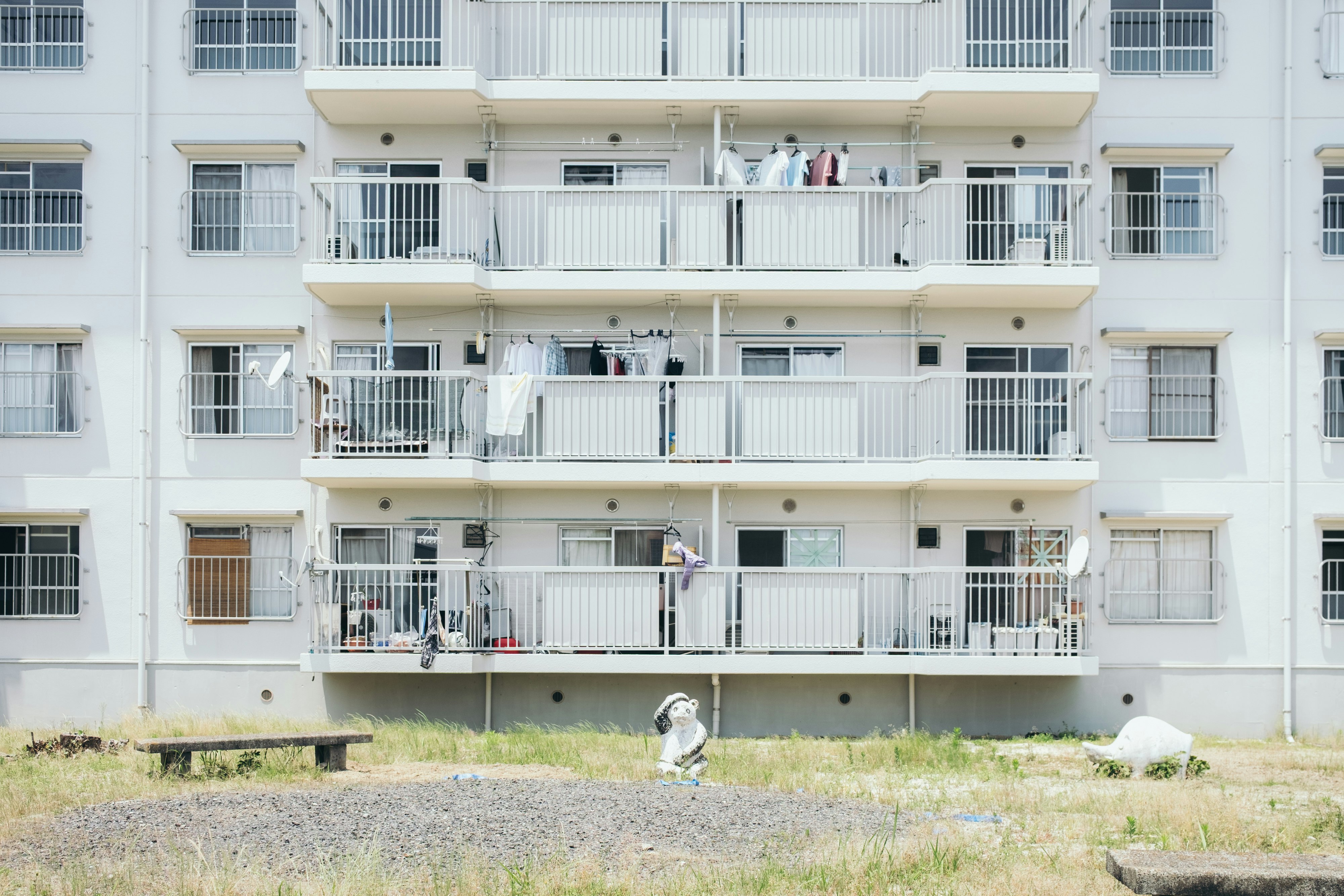 白い集合住宅のバルコニーと洗濯物のある外観