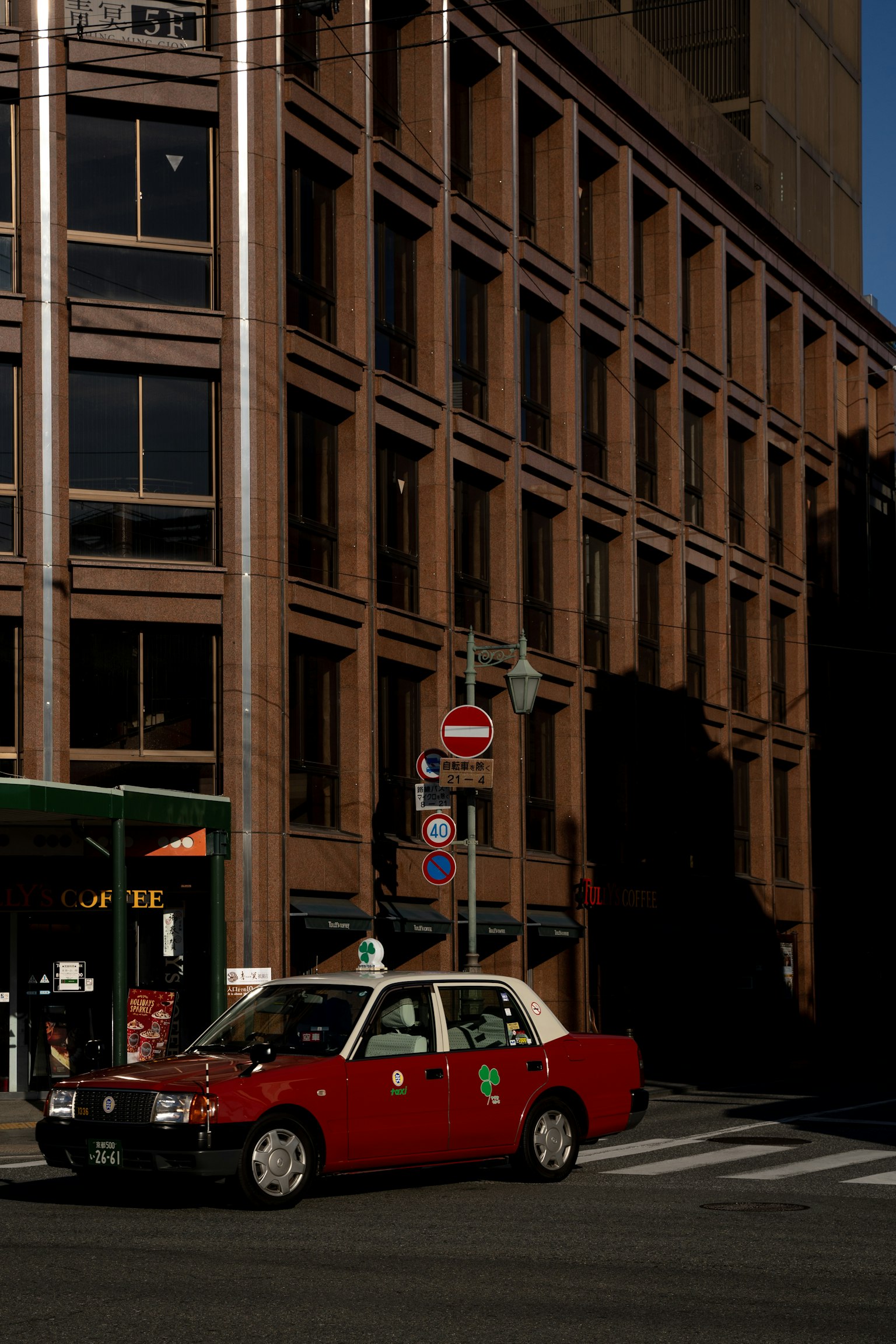 Un taxi rosso parcheggiato all'angolo di una strada davanti a un edificio moderno