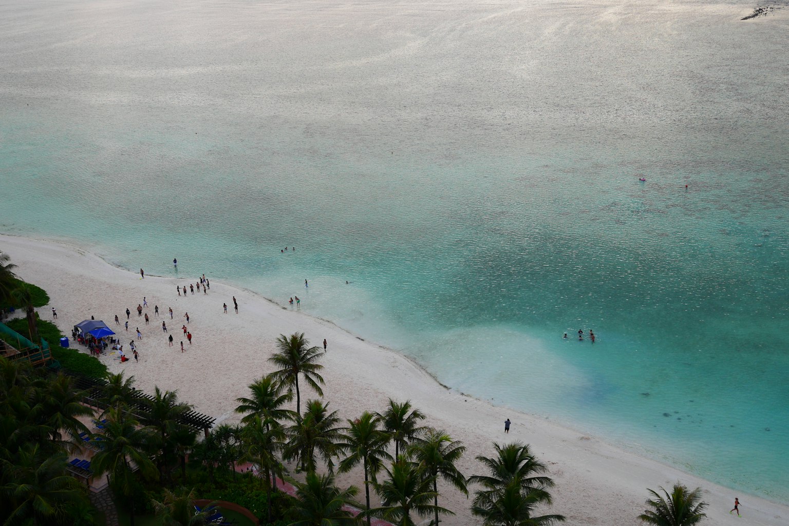 Beach scene with blue ocean and white sand people enjoying the water