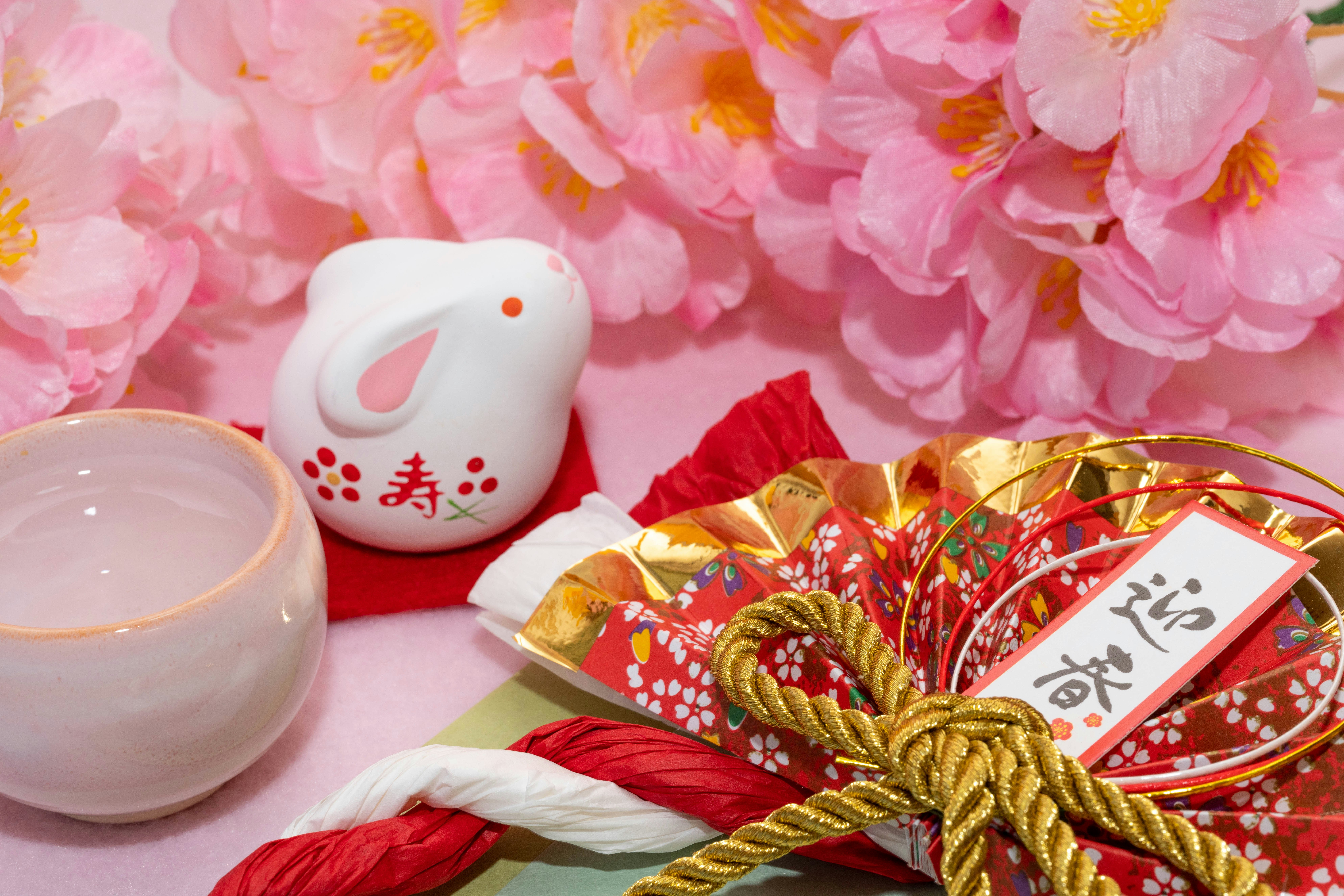 日式新年裝飾桌面，粉色花朵與幸運護符