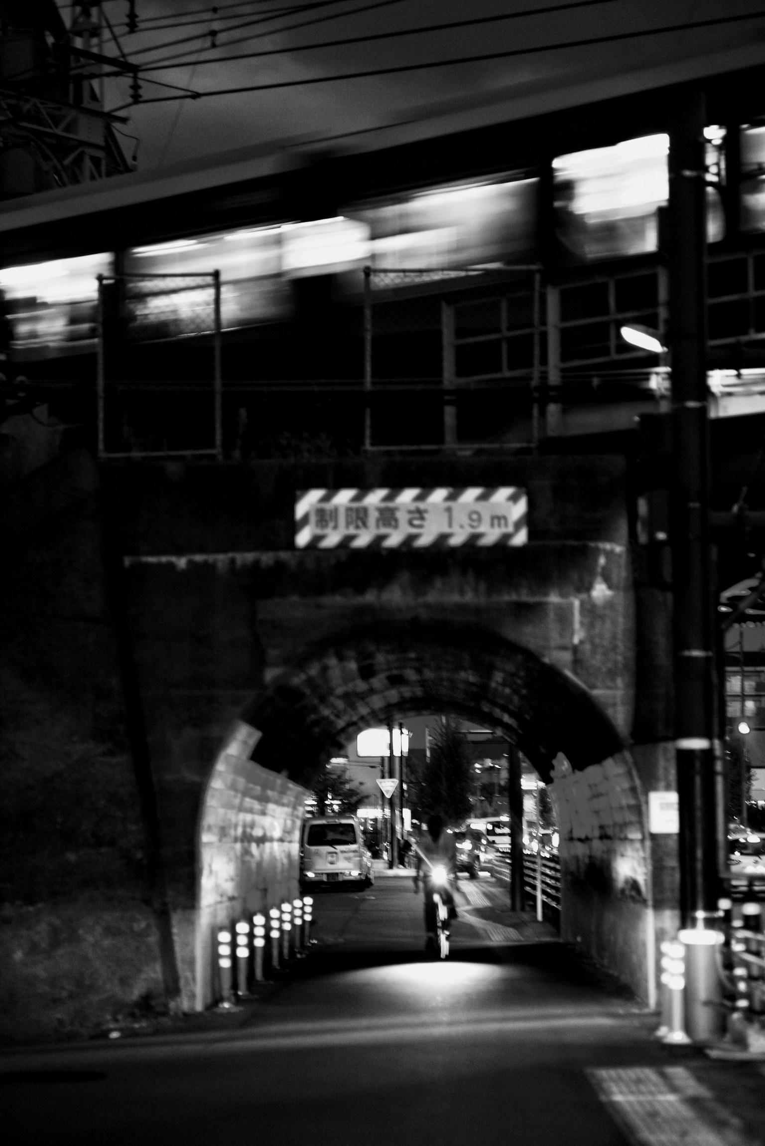 Kereta melintas di bawah jembatan busur dalam suasana malam kota