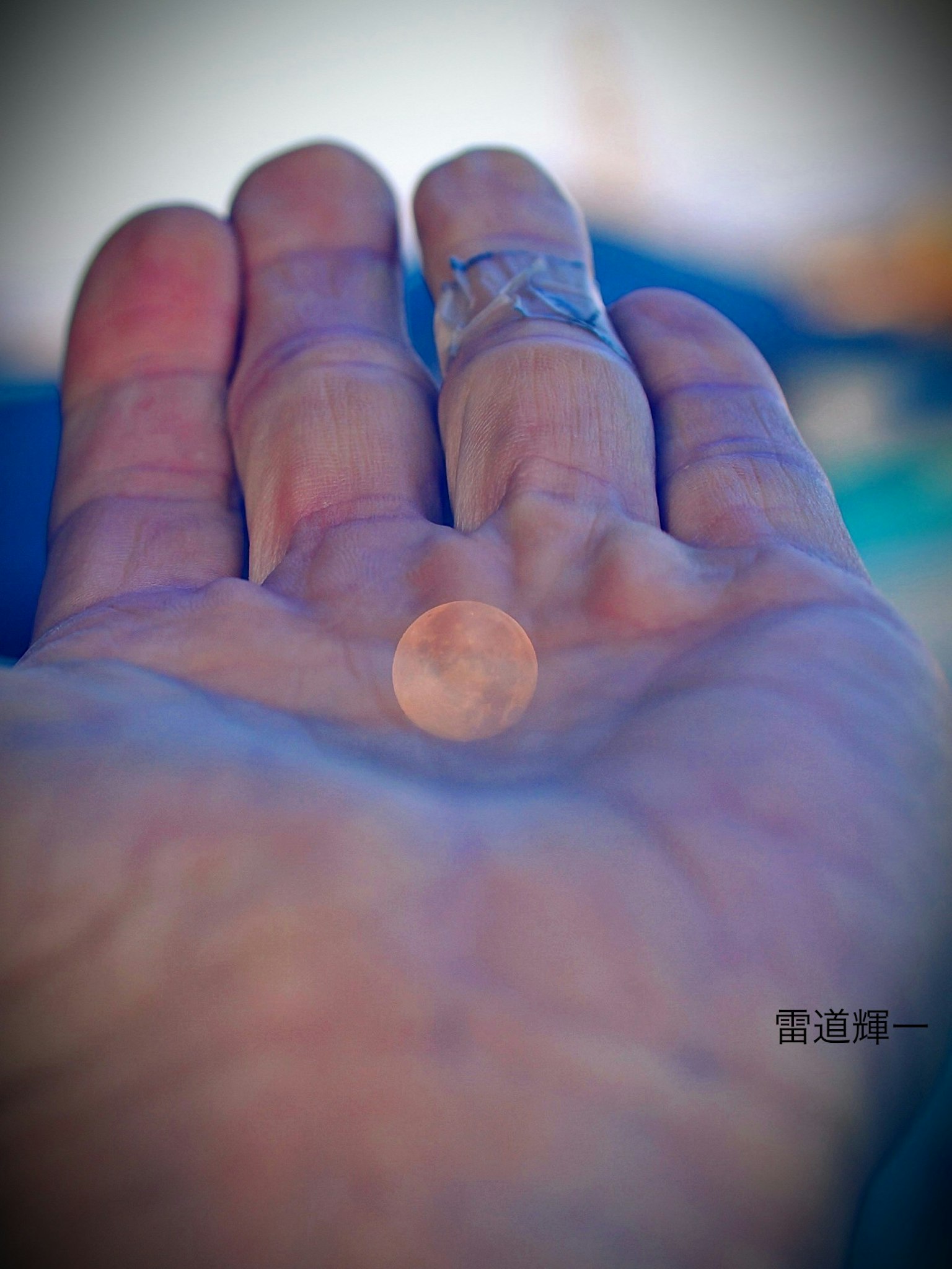 手のひらに小さなコインが乗っている画像 手のひらは青い背景に対して明るく見える