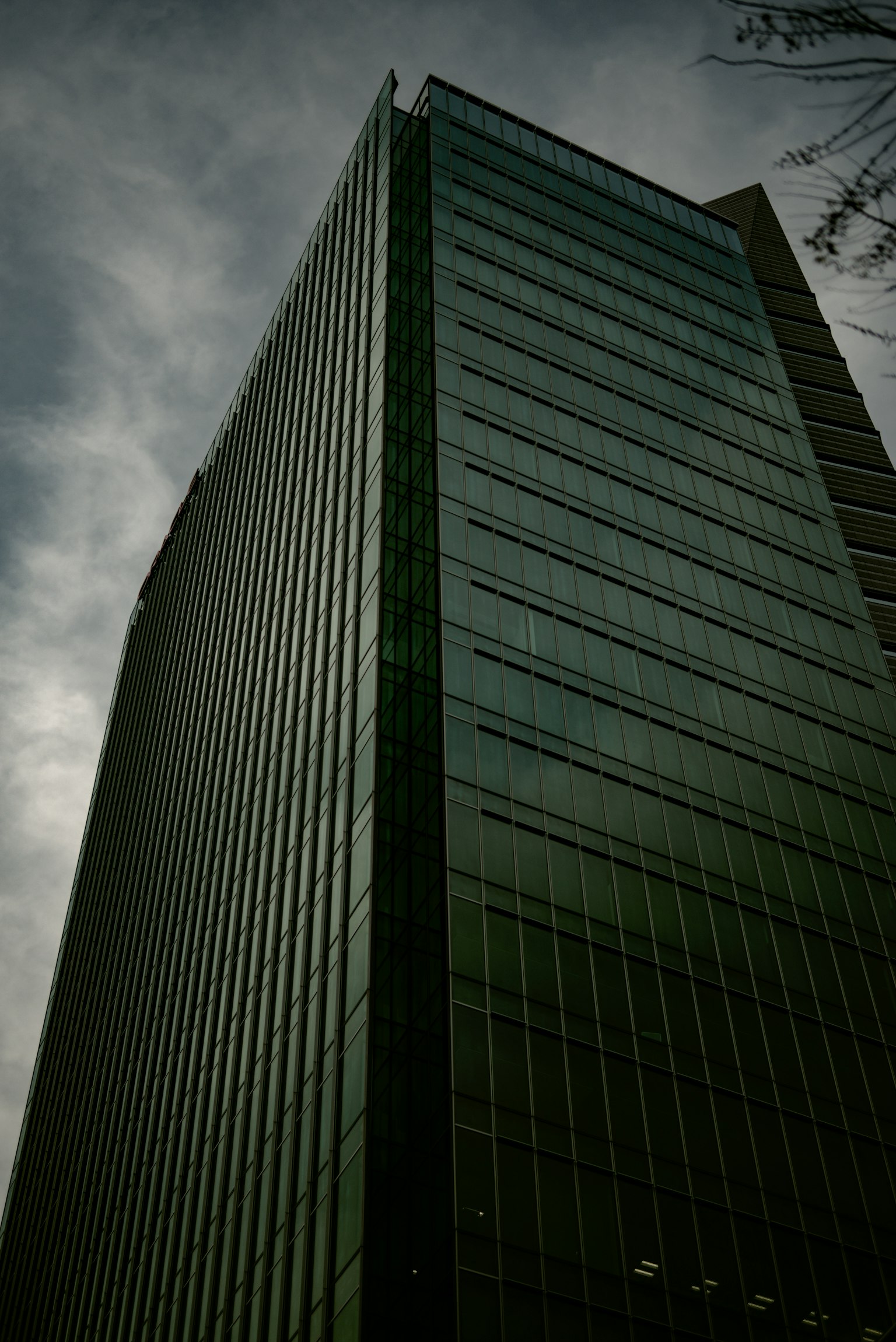 높은 건물과 구름이 낀 하늘 배경의 녹색 유리 외관
