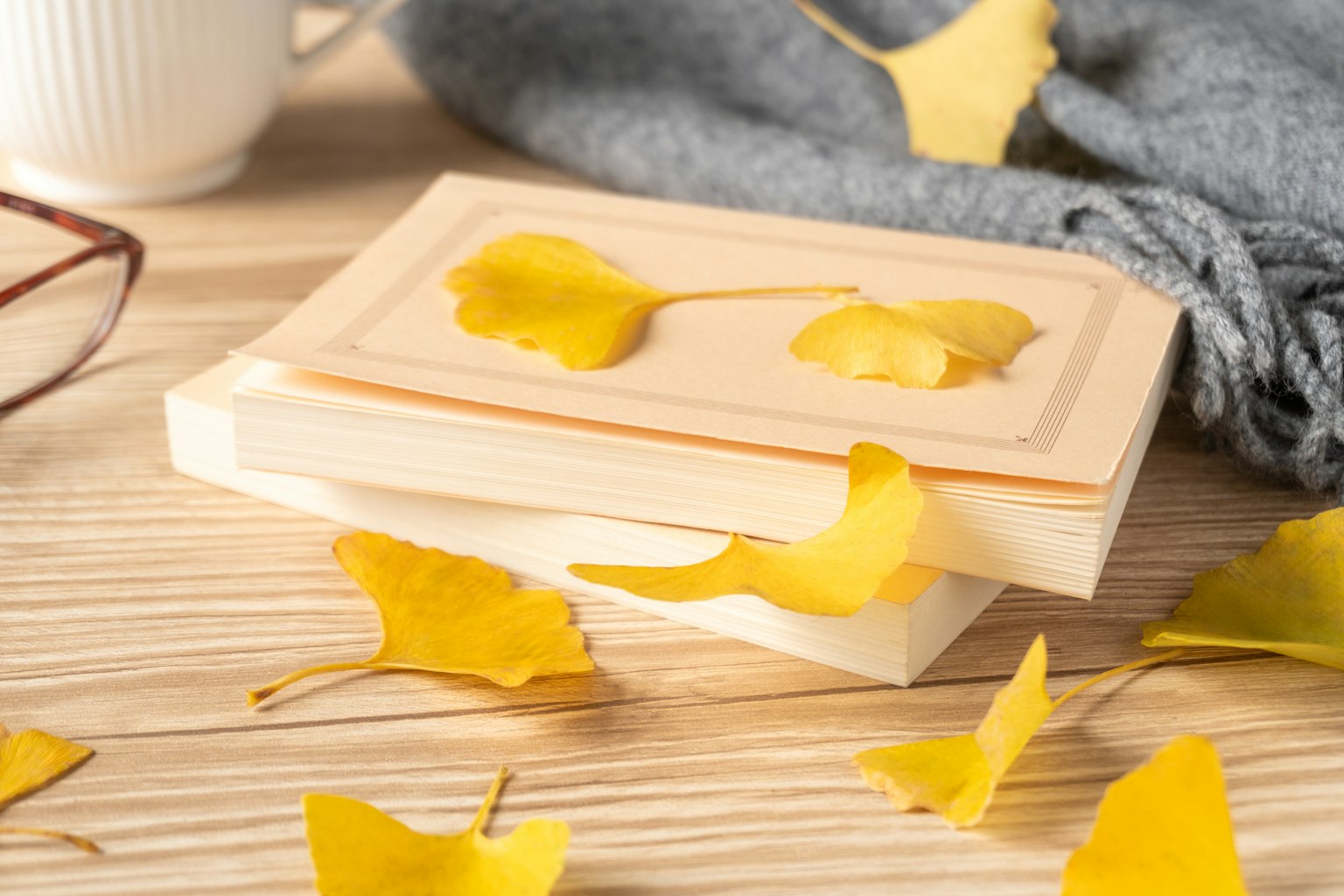 Livre en bois avec des feuilles de ginkgo jaunes éparpillées sur une table en bois