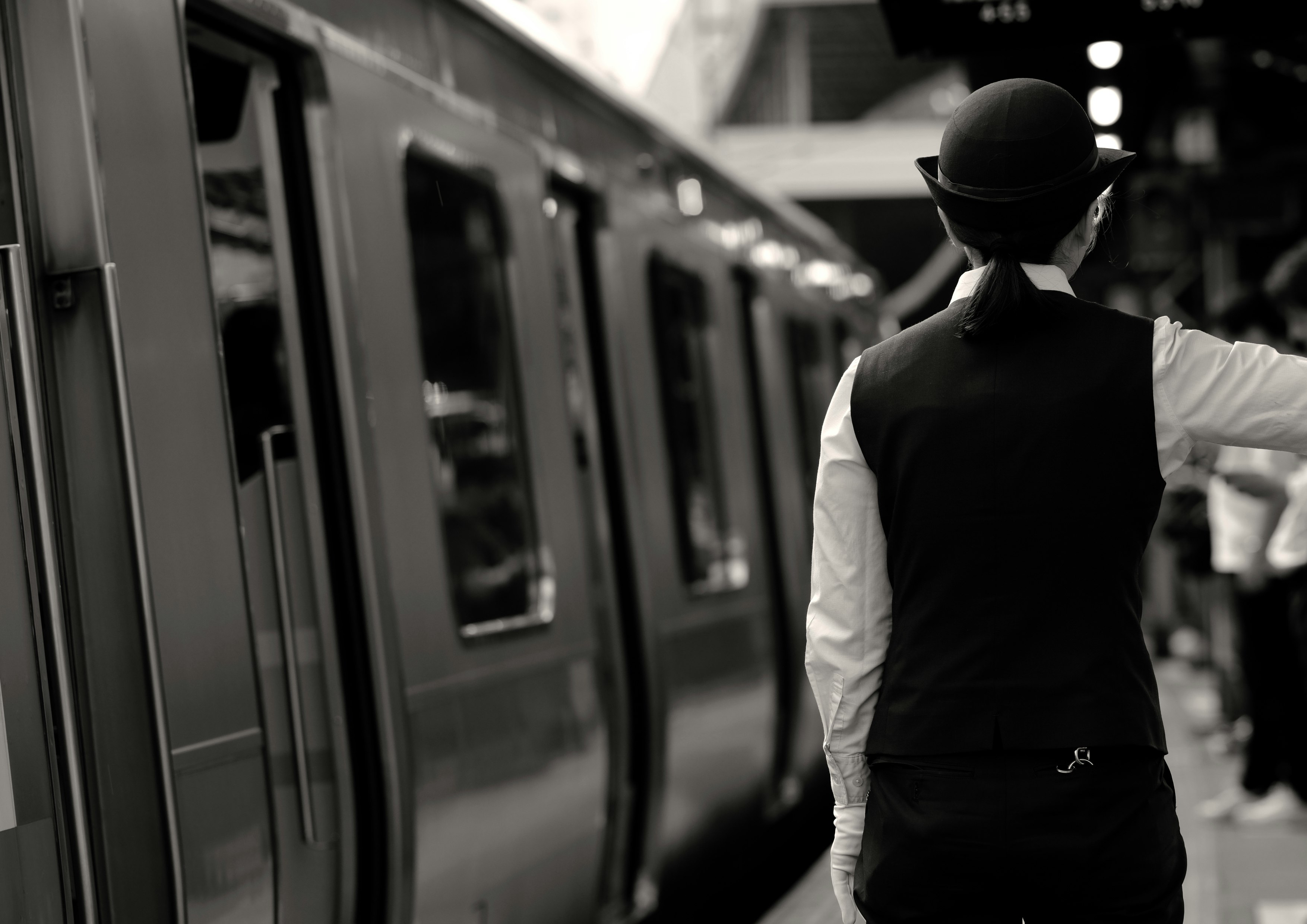 駅のホームで電車を見つめるベスト姿の男性
