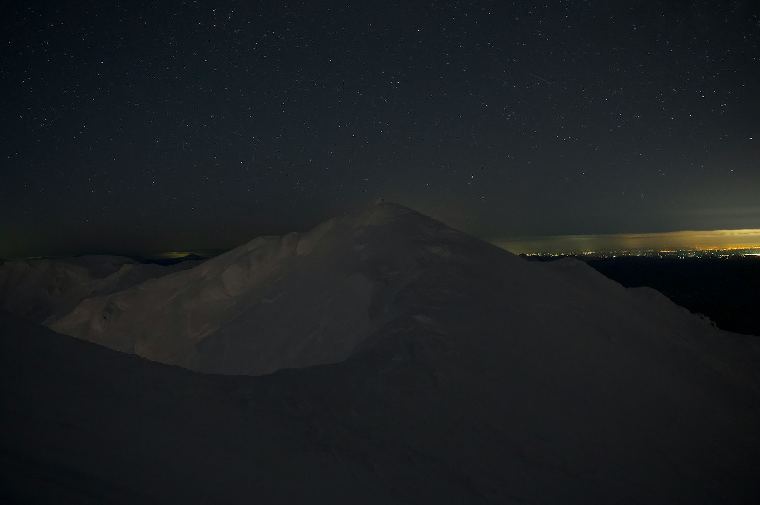 Silhouette of a snow-covered mountain under a starry sky